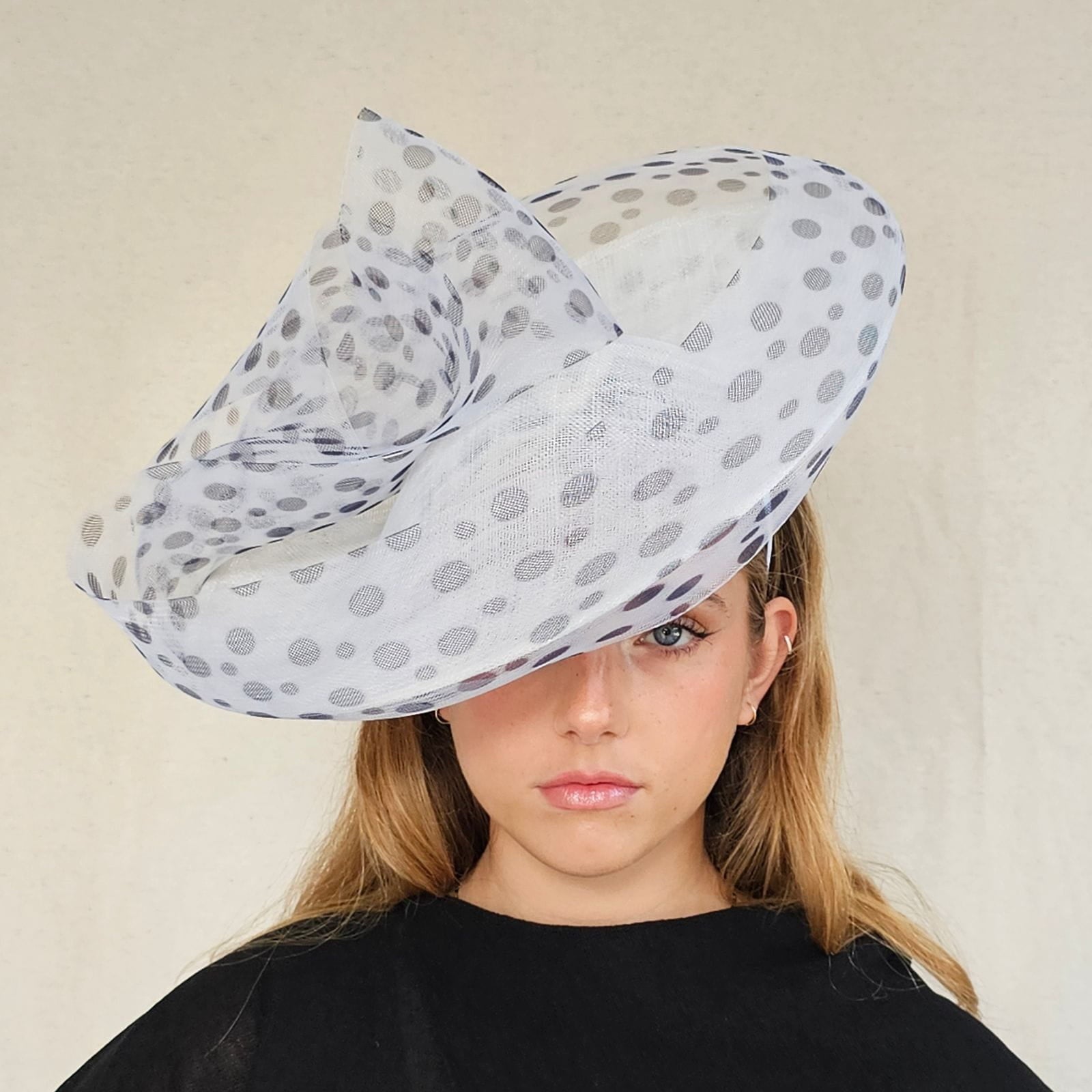 White ascot disc hat with black spotted crin swirl embellishment, front view.