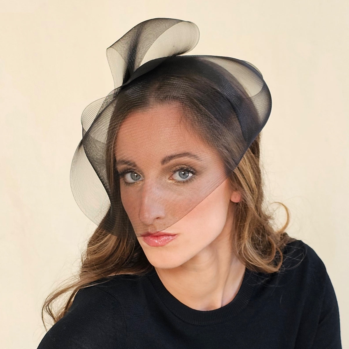 Front view of black crin headband with sculptural loops and face
veil.