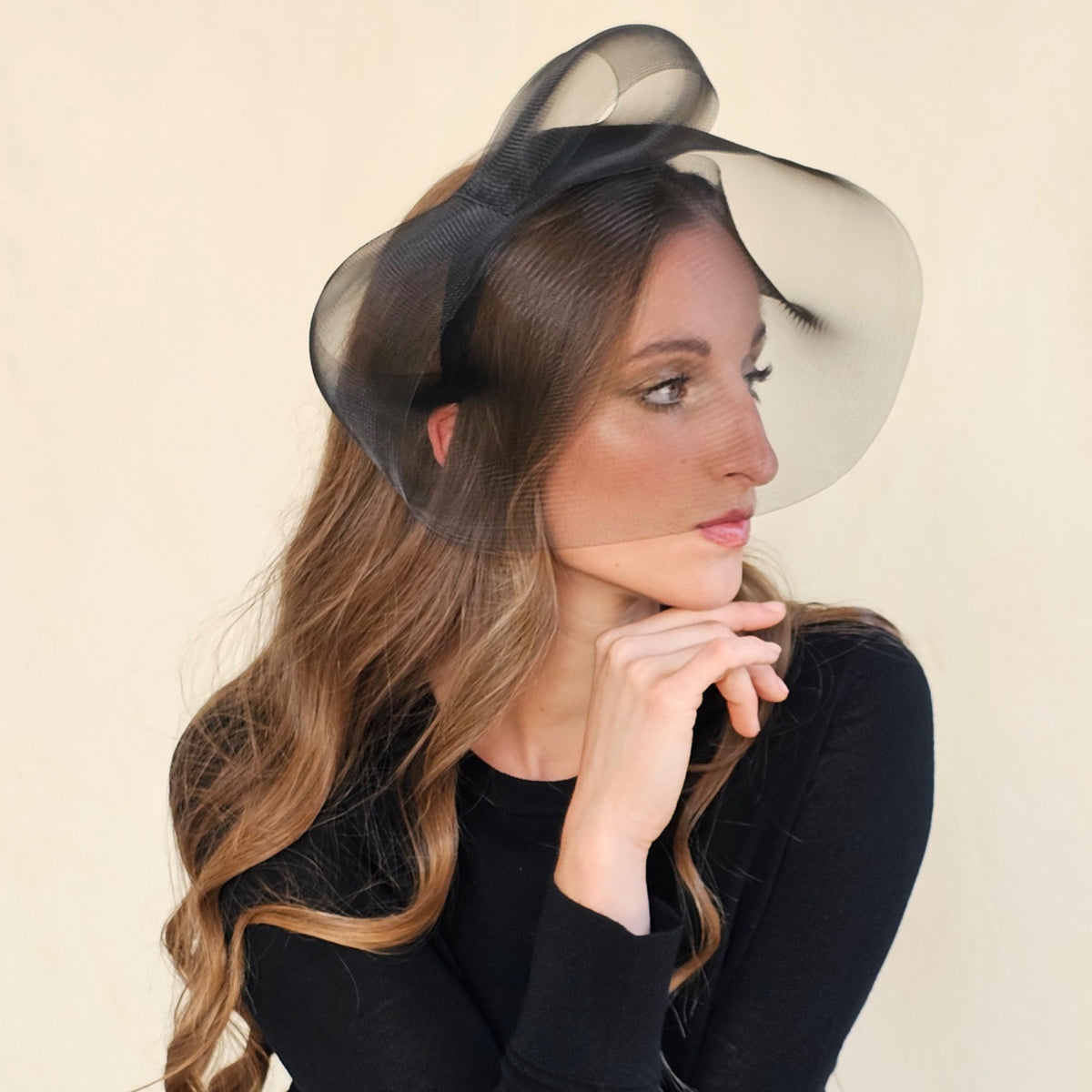 Side view of black crin veil headband on a model resting her chin
on her hand.