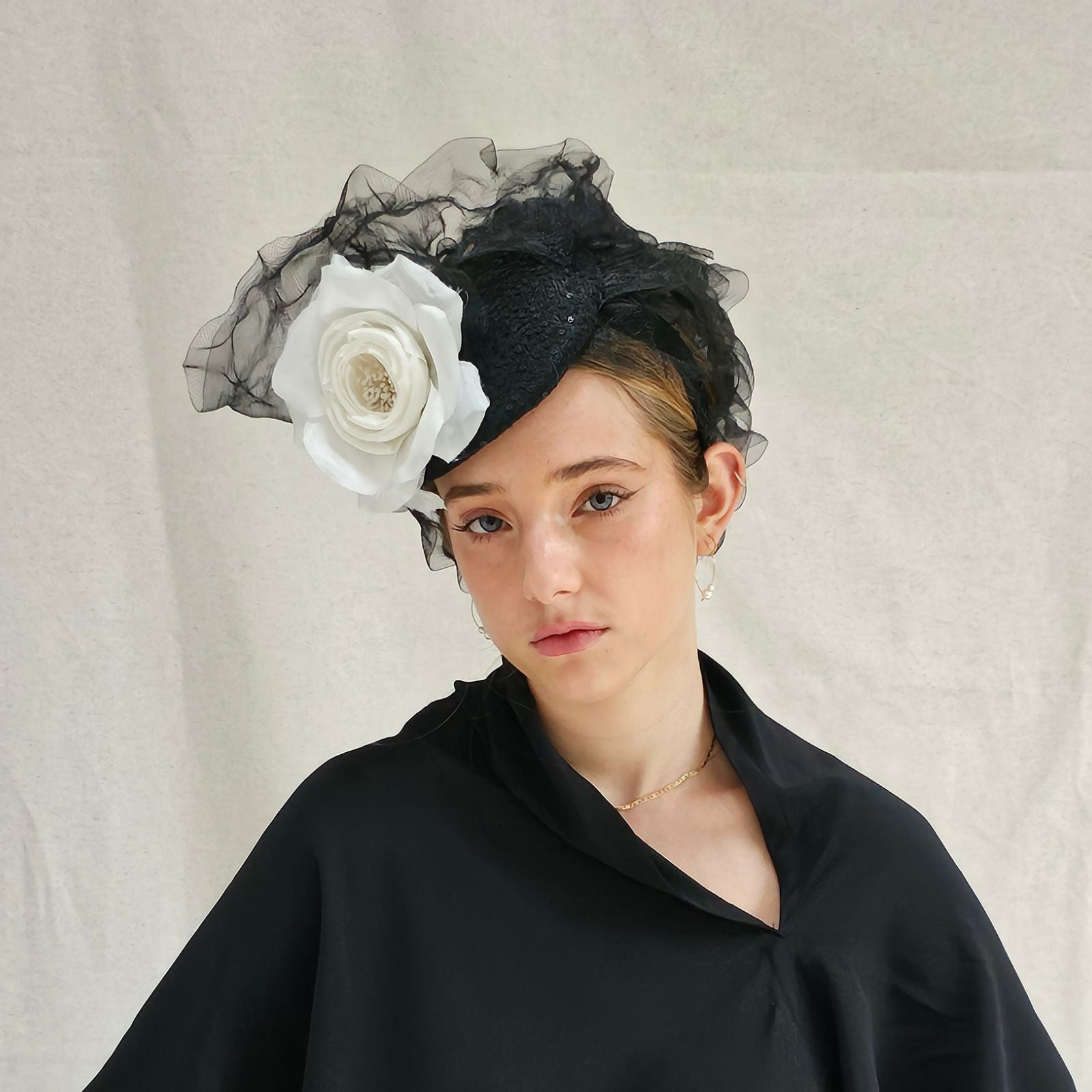 Black turban hat with ruffle swirl crin and dramatic white flower, front view.