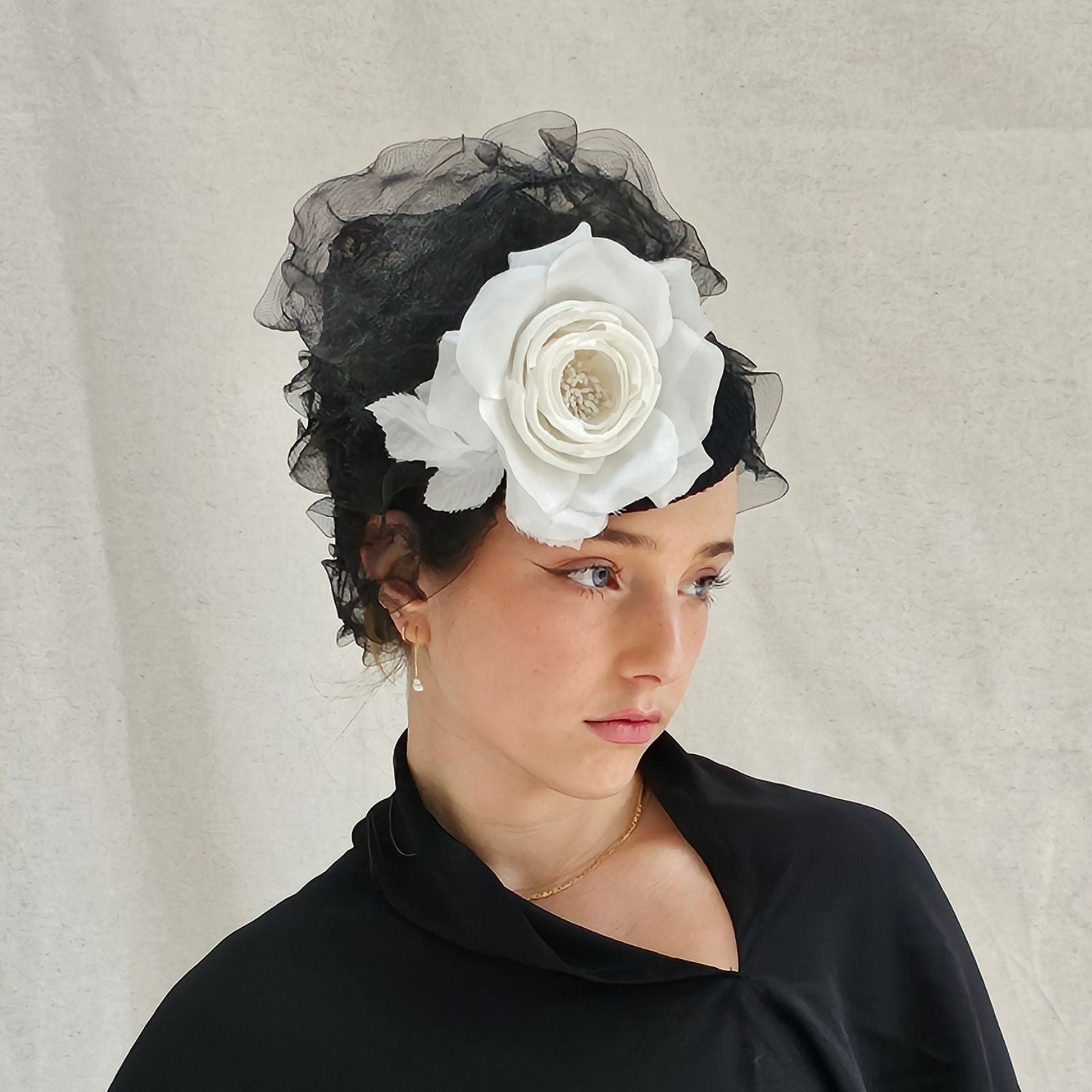 Black crin turban hat with elegant ruffle swirls and dramatic white flower, right angle view.