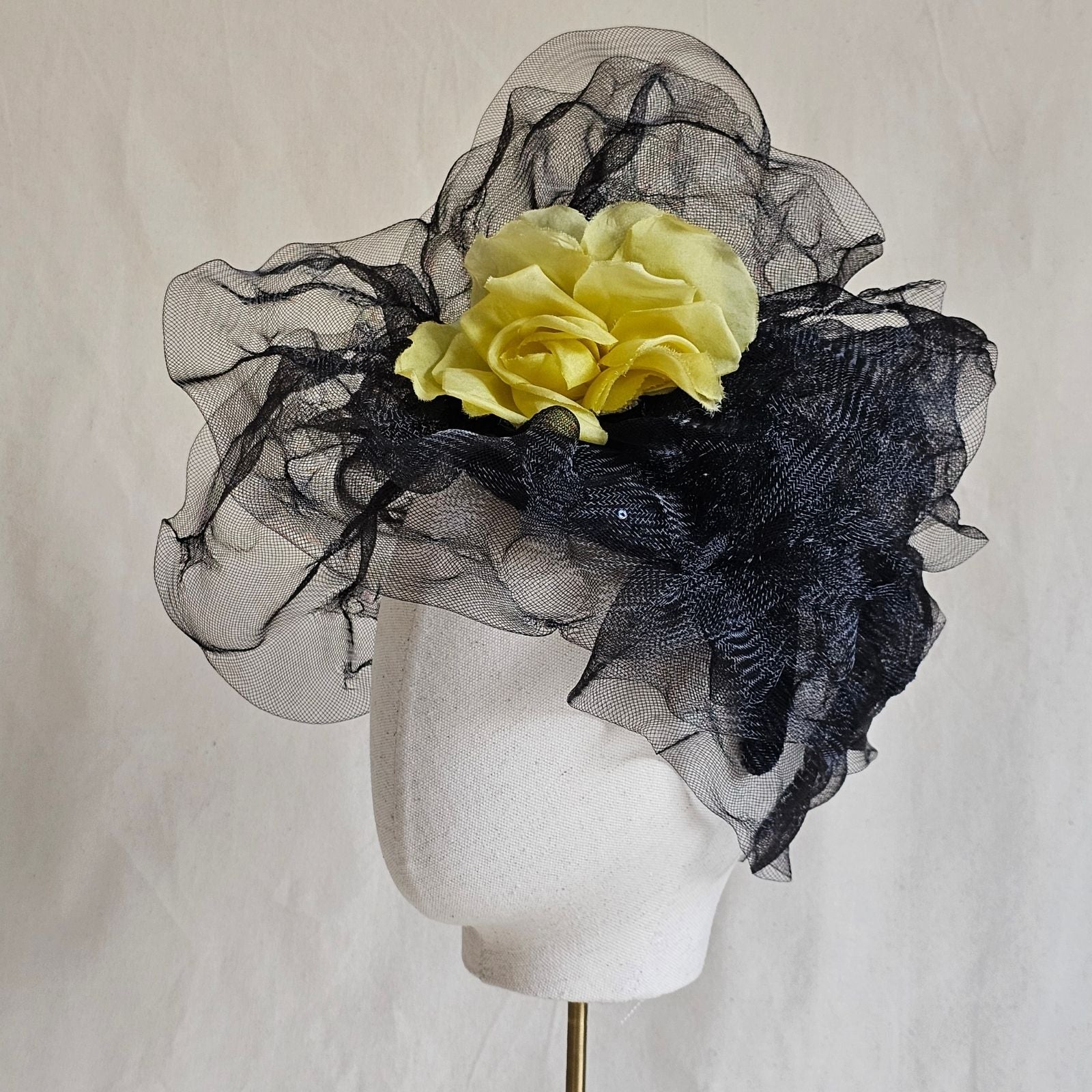 Black crin turban hat with striking yellow flower, left view.