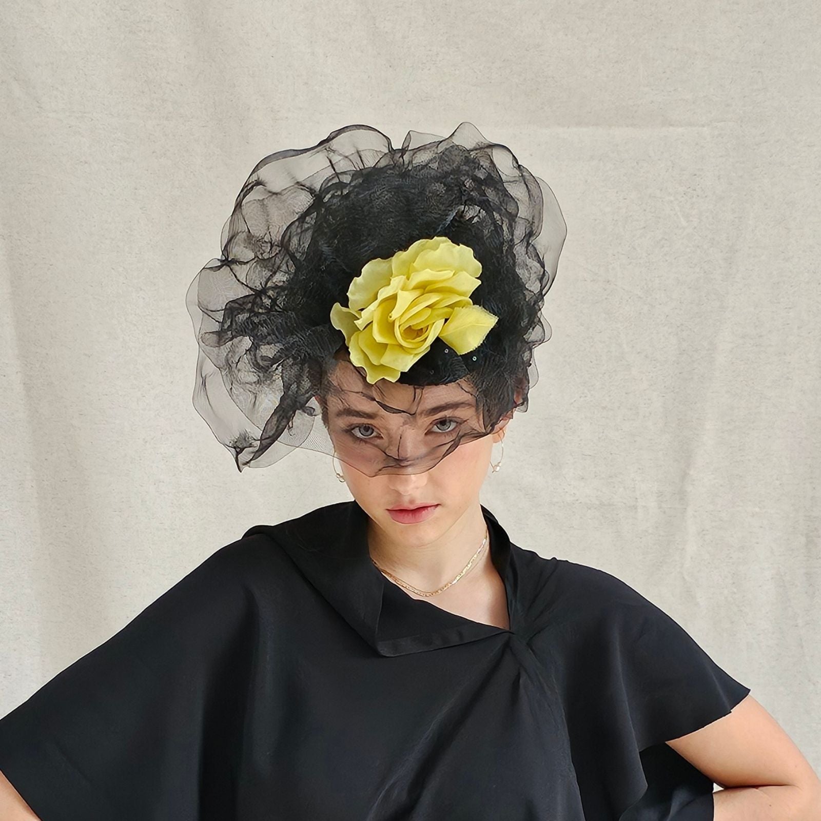 Black turban hat with dramatic crin swirl veiling and yellow flower embellishment, front view.