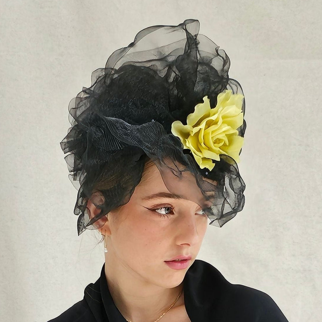 Black turban hat with dramatic black crin veiling and bold yellow flower embellishment, right view.