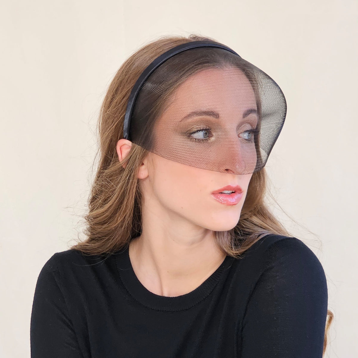 Angled view of black crin face-cage headband showing its curved
outline.