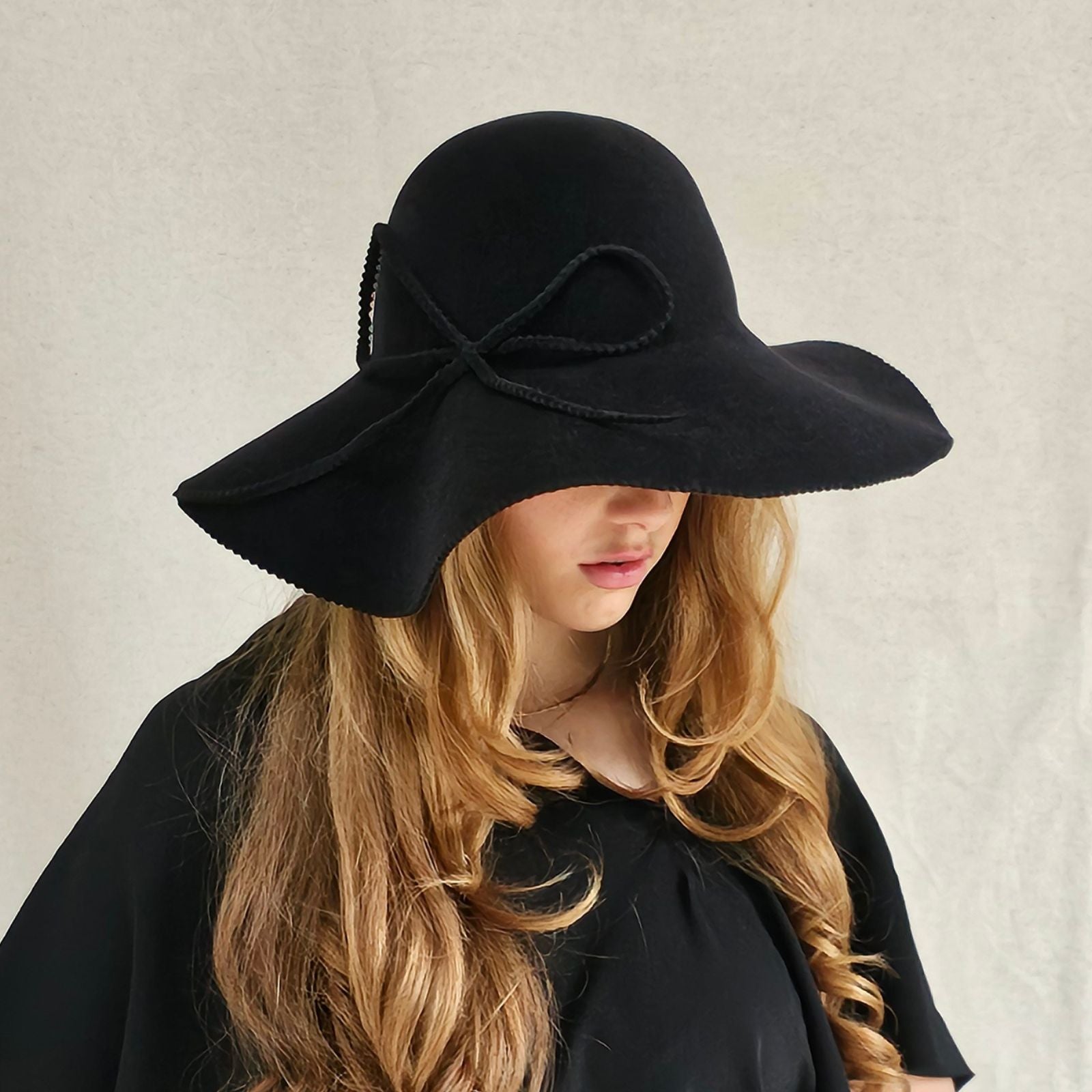 Black felt 1970s hat with elegant bow embellishment, front view.