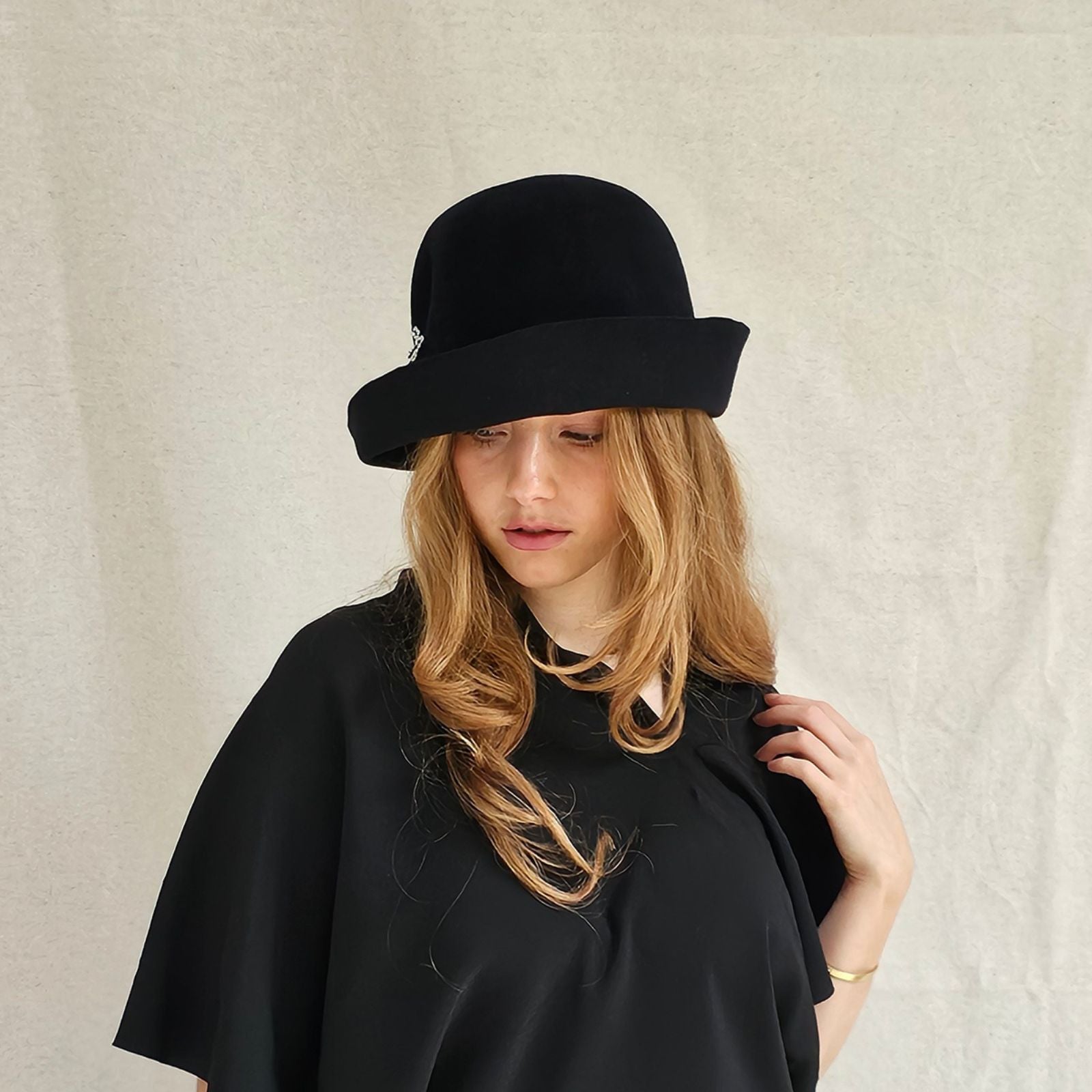 Black felt cloche hat with beautiful bow embellishment, left view.