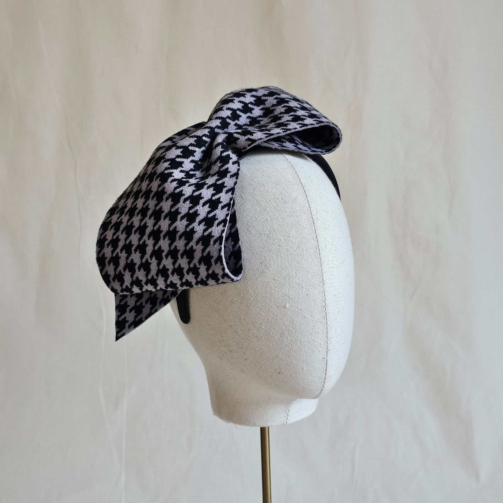 Headband with black grey houndstooth felt bow, angle view.