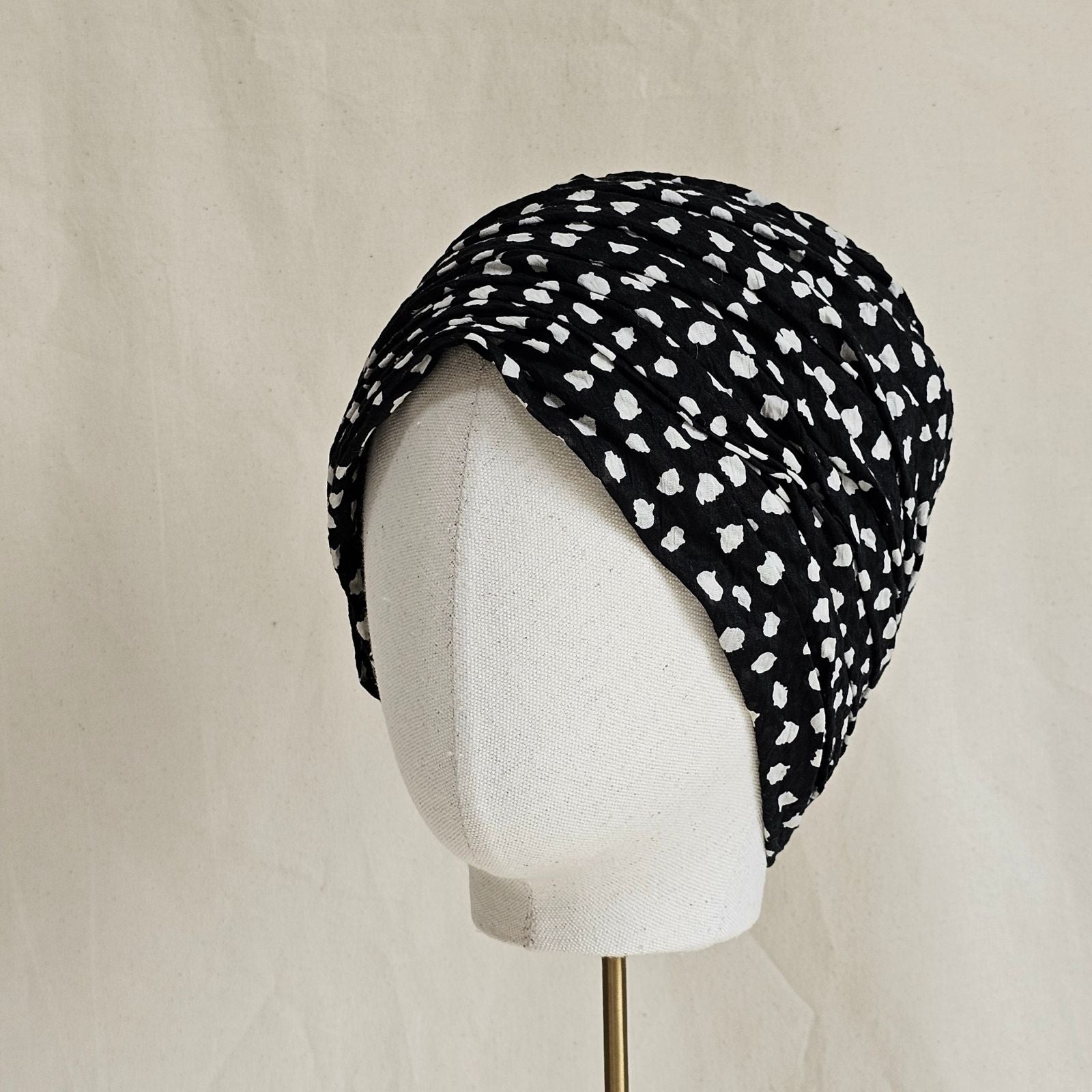Black gathered cotton turban with ivory dot pattern, side view.