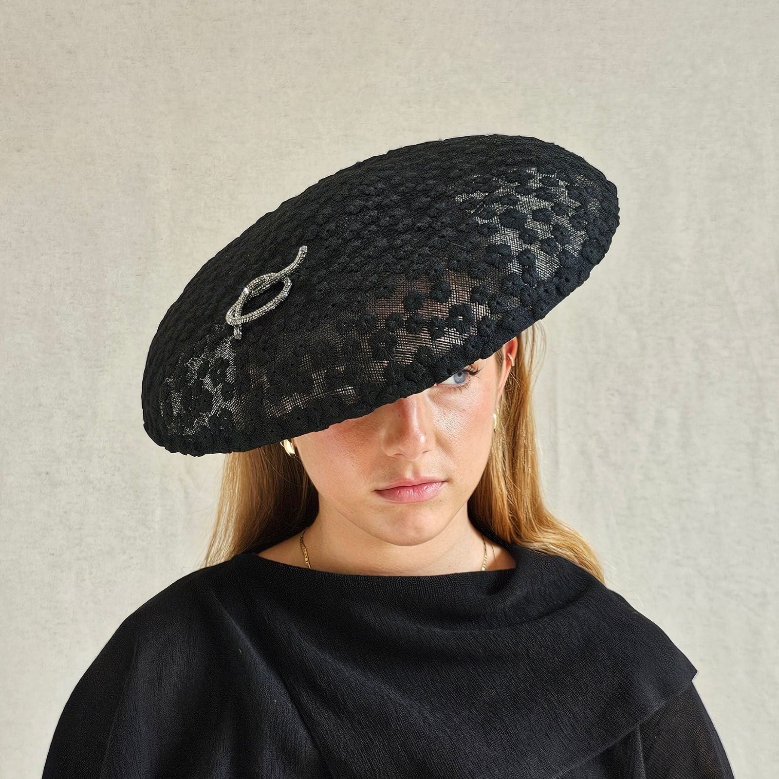 Black lace disc hat with beautiful silver pretzel knot embellishment, front view.