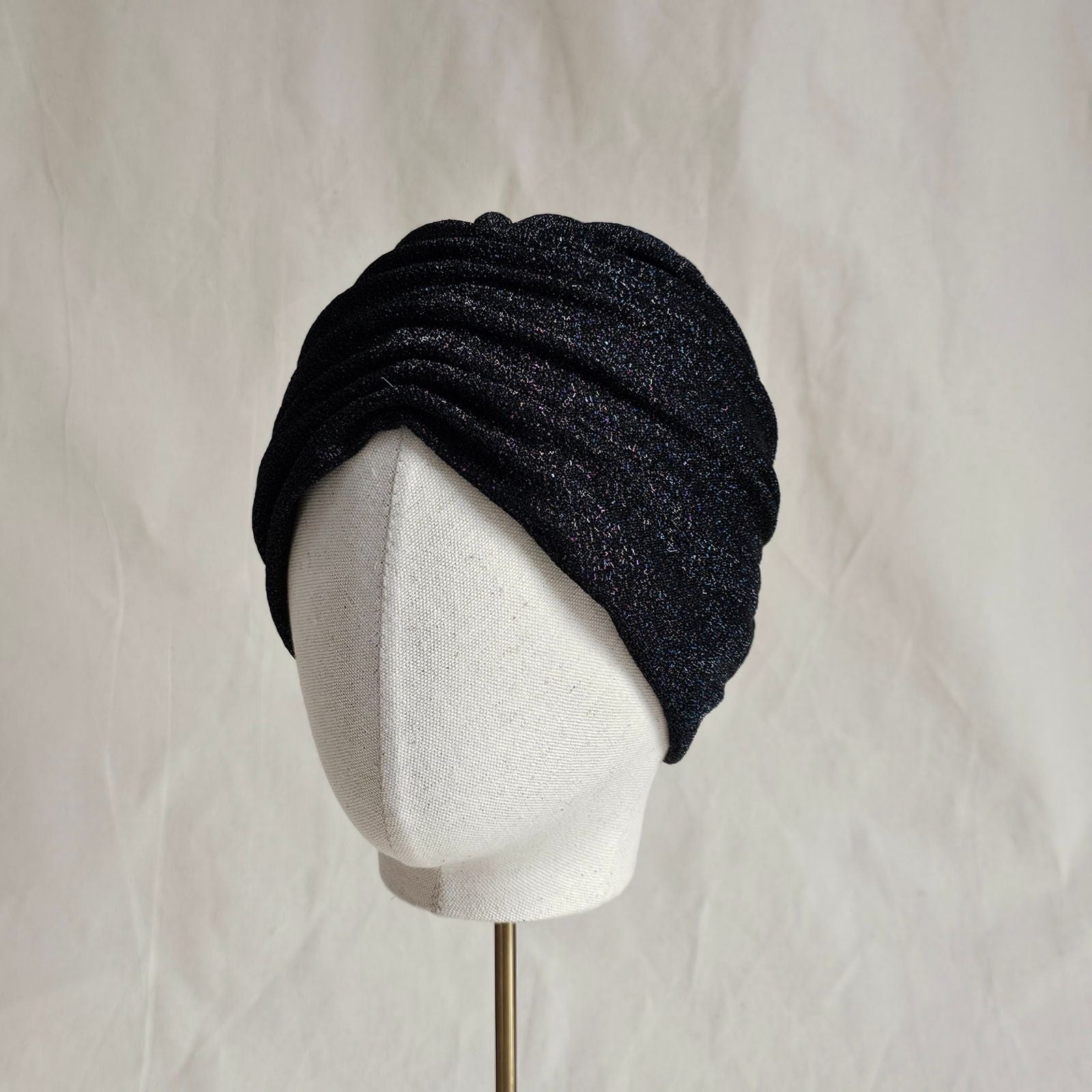 Black lurex turban with loosely gathered front, angle view.