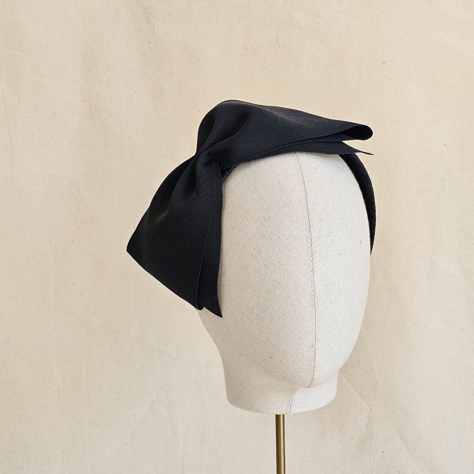 Black wide petersham bow on a headband, angle view.