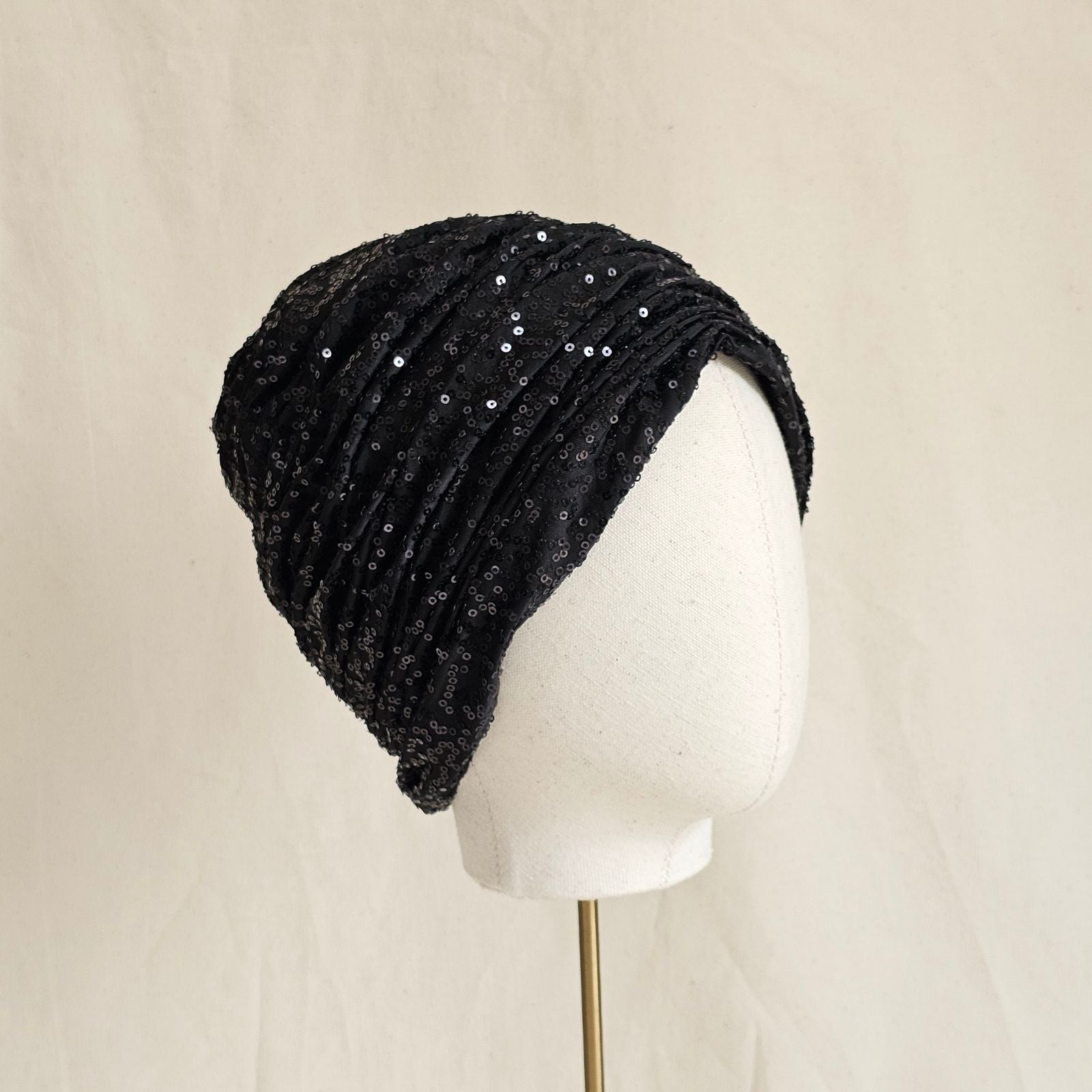 Black sequin turban beauifully gathered, angle view.