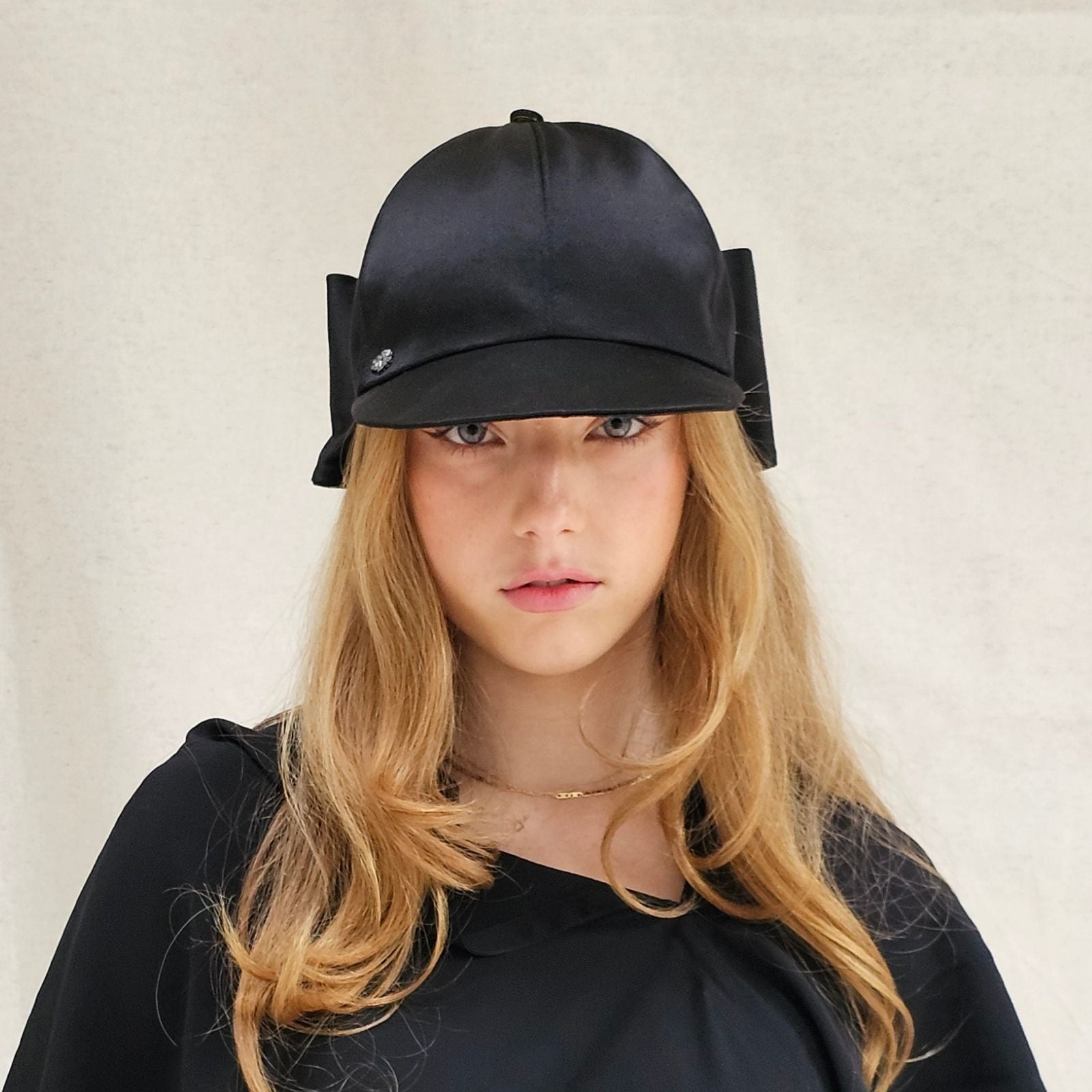 Black silk baseball cap with dramatic bow, front view.