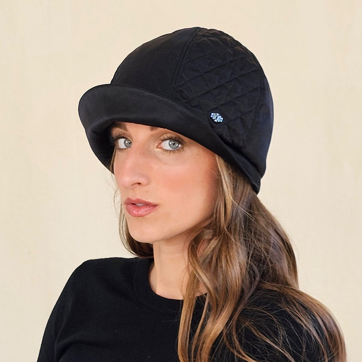 Angled view of black silk satin cloche with quilted panel and curved
brim.