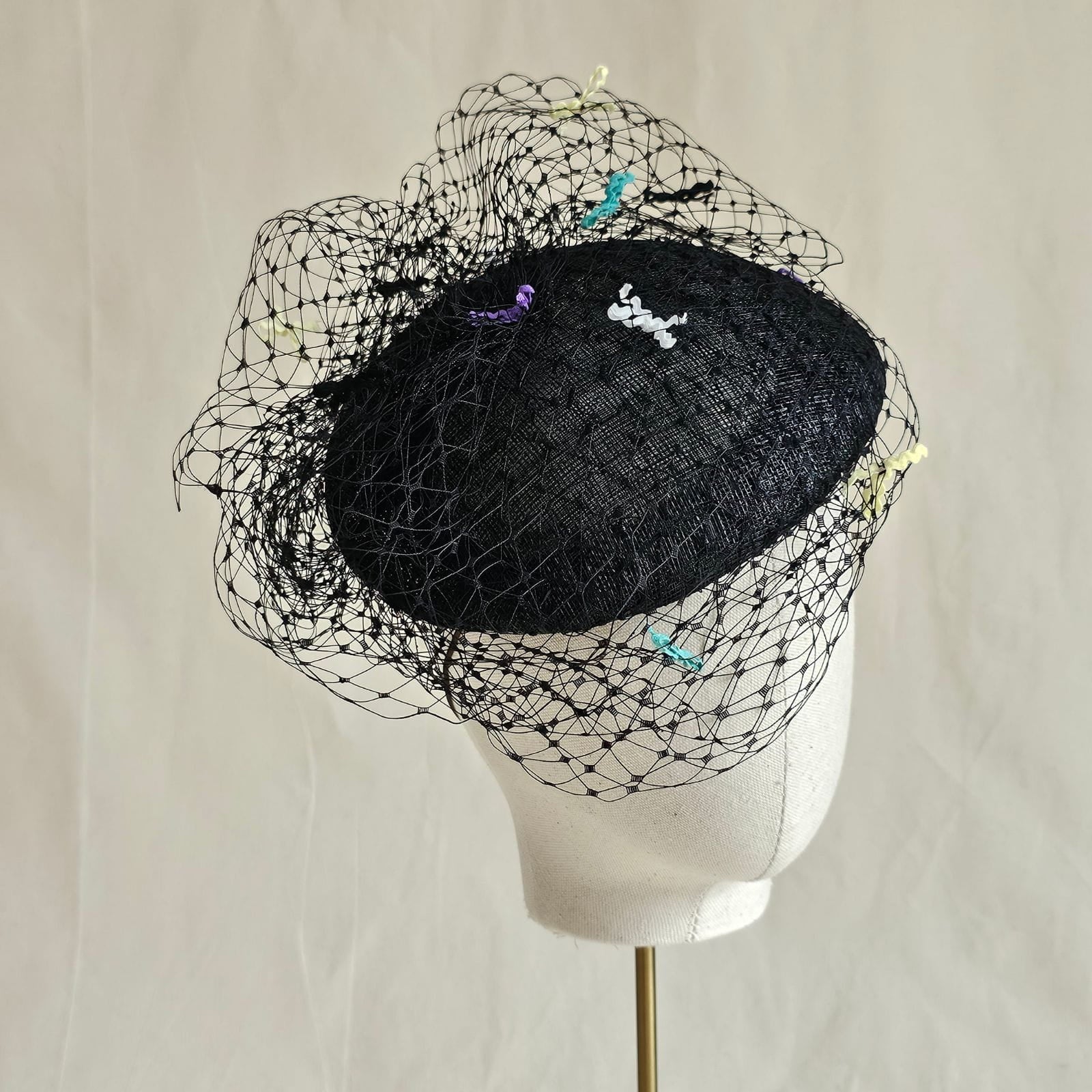 Black sinamay beret with beautiful veil and multicolour bow detailing, angle view.