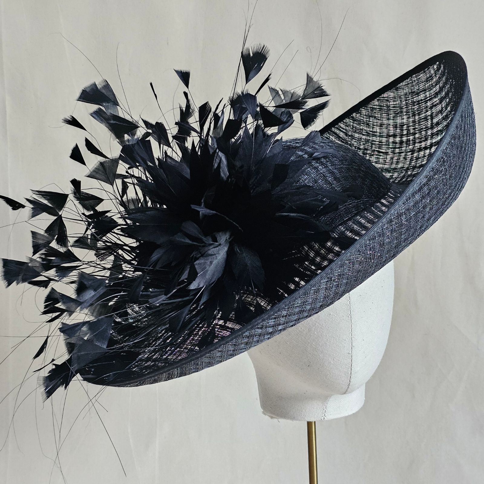 Black siname breton hat with beautiful feather flower, angle view.