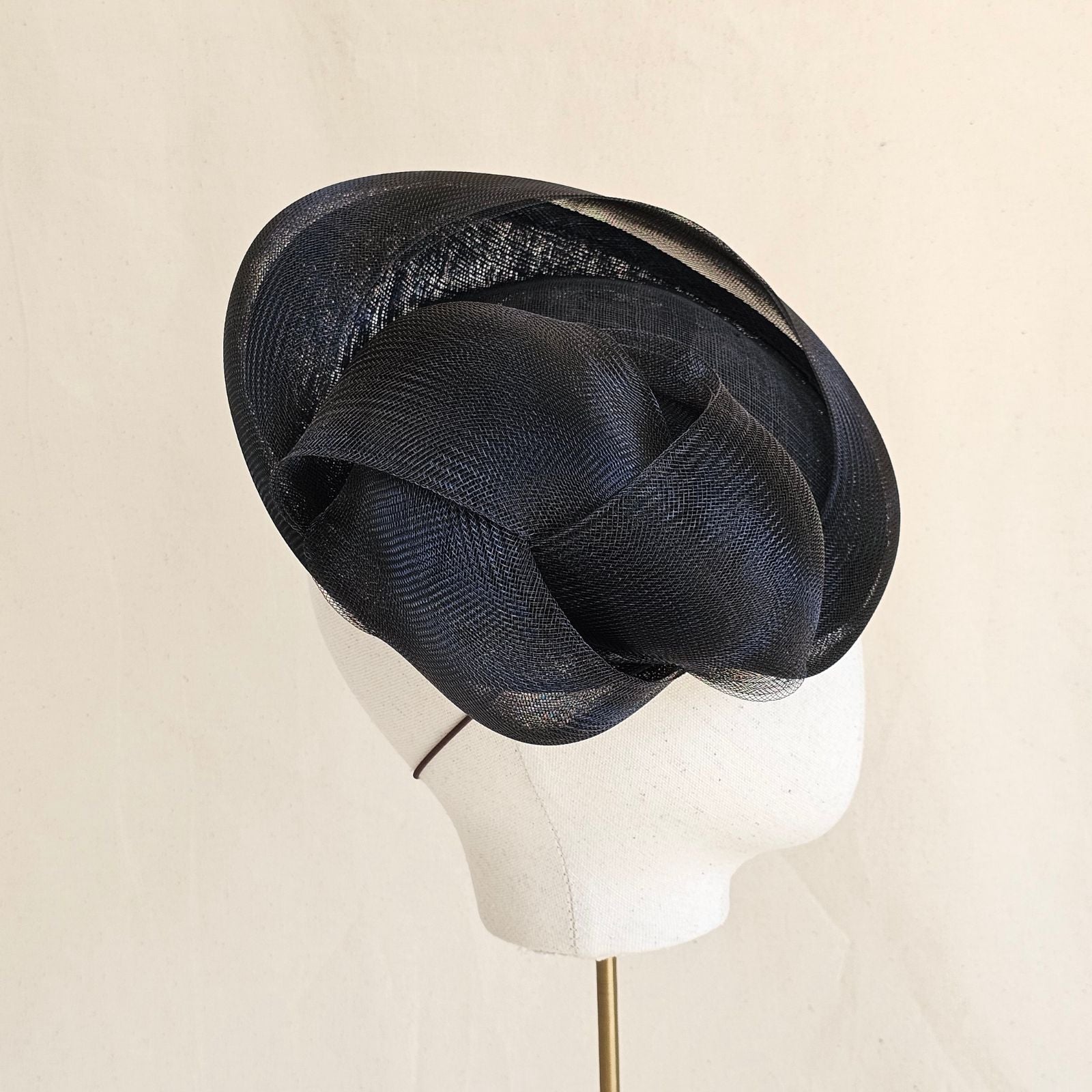 Black straw disc hat with sculptural crin knot, rear side view.