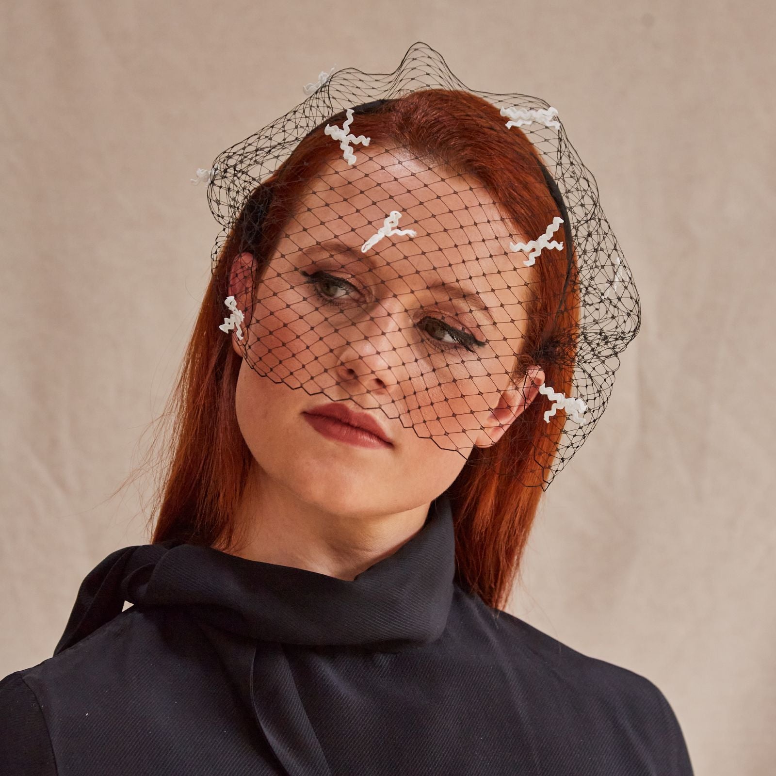Black headband with veil and ivory bow detailing, front view.
