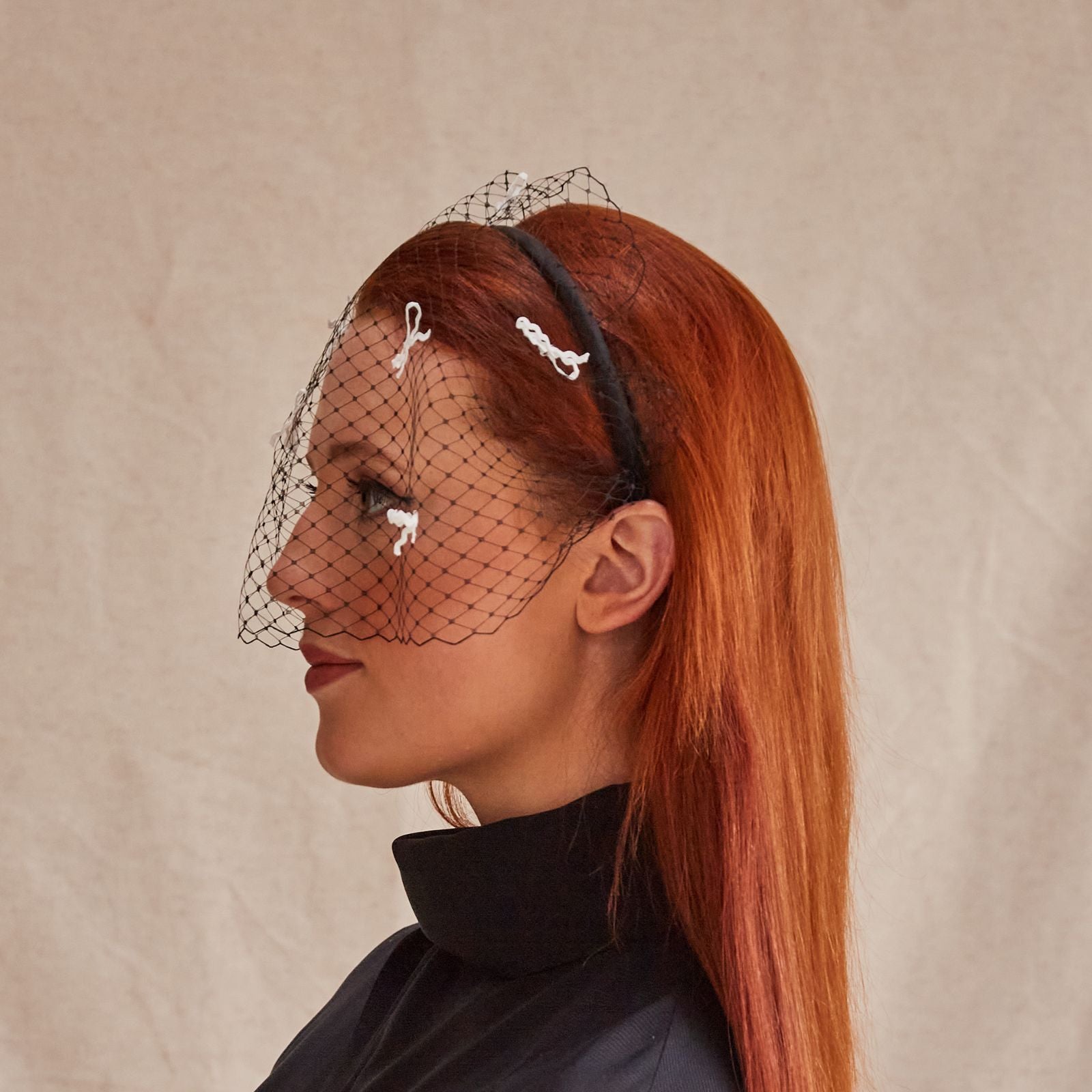 Black headband with veil and ivory bow detailing, side view.