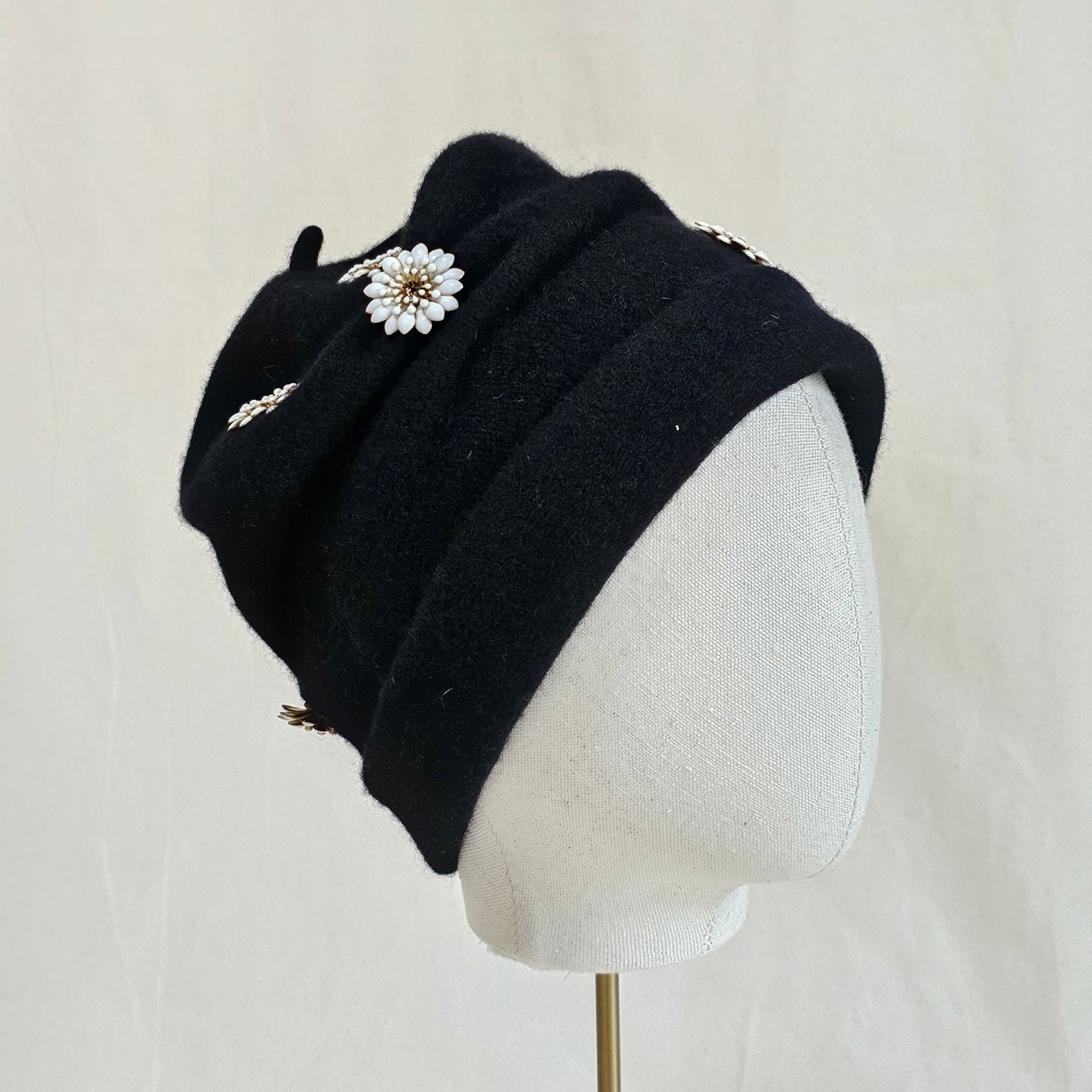 Black wool beanie with beautiful white daisy embellishments, back view.