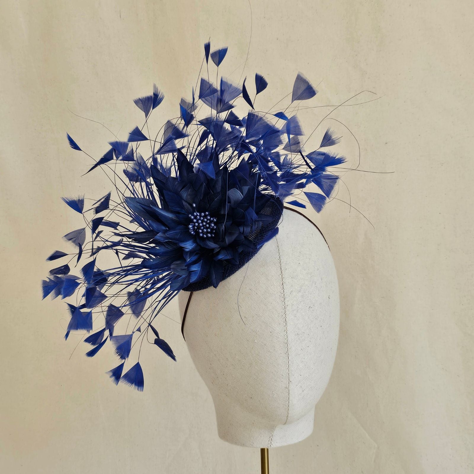 Blue feather fascinator with feather flower, front view.