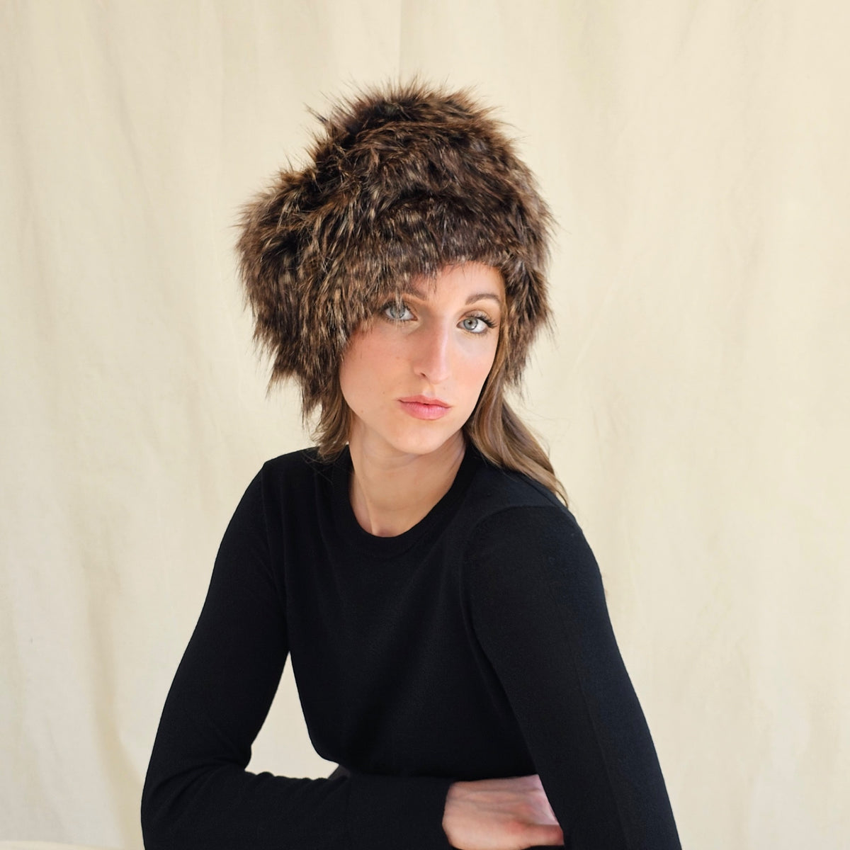 Brown and black raccoon print faux fur pillbox hat, worn on a
model.