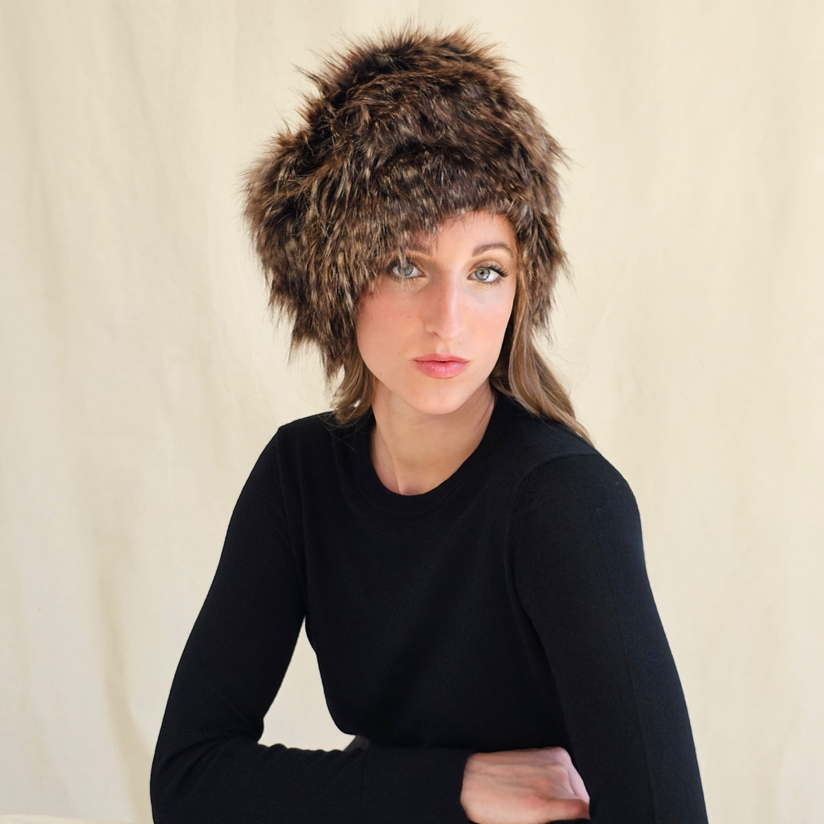 Front view of brown and black faux fur pillbox hat on a seated
model.