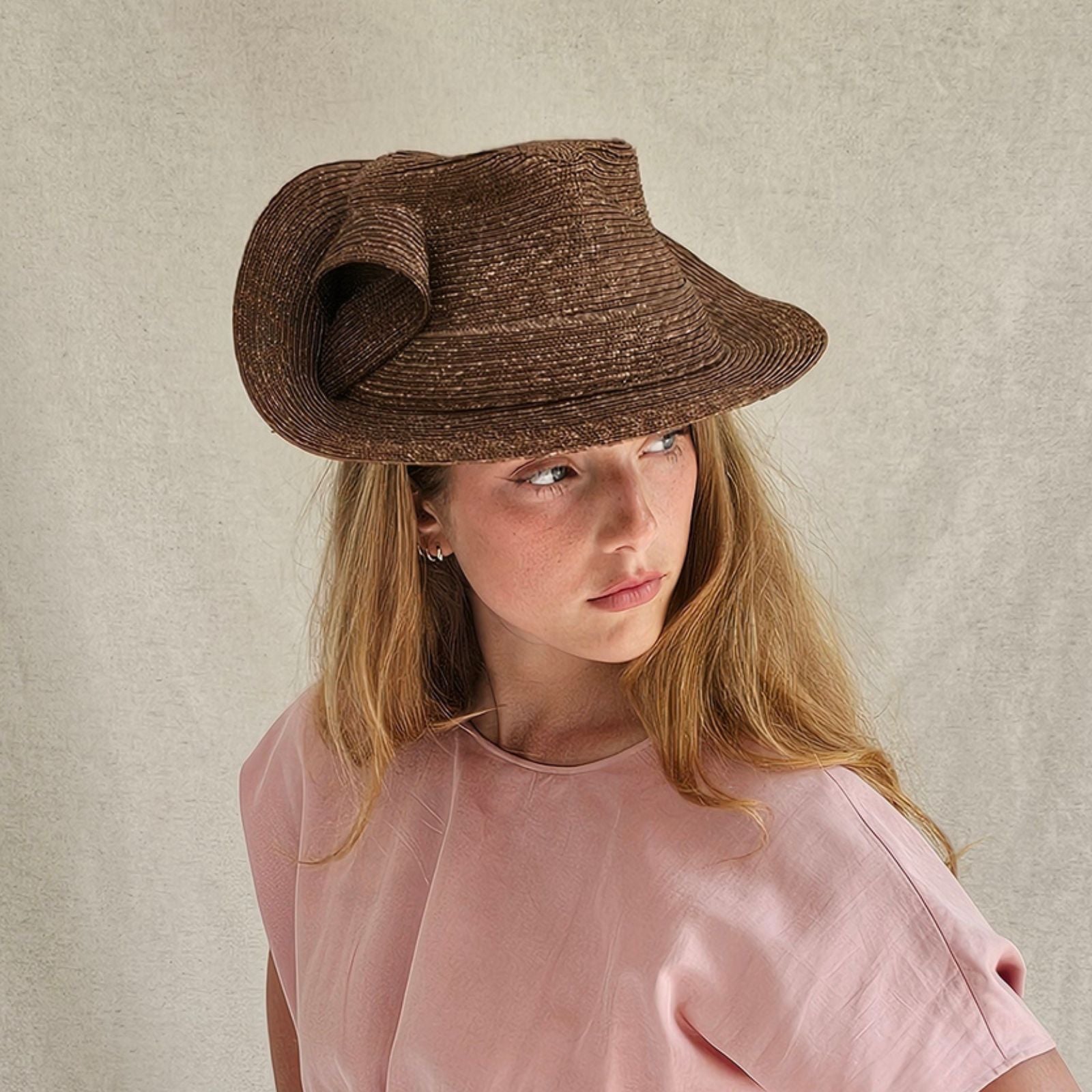 Brown straw trilby with elegant bow swirl, side view.