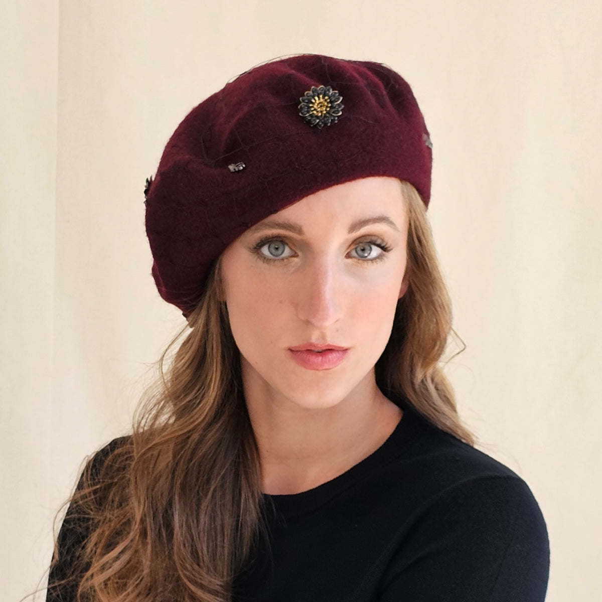 Burgundy wool beret with dark flower embellishment and
monograms on model.
