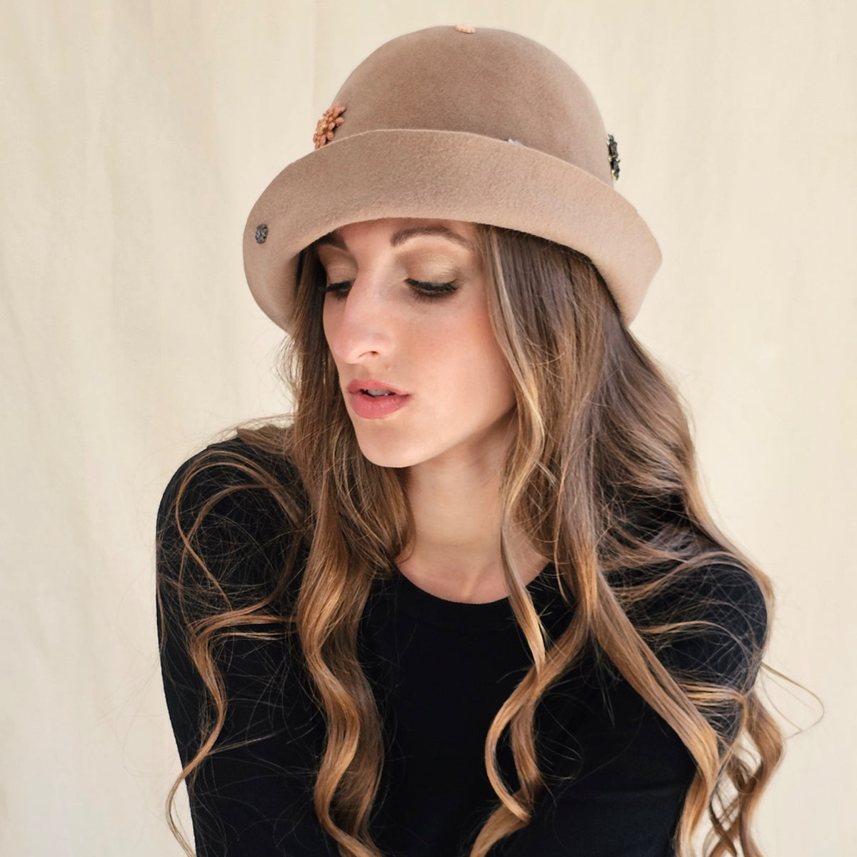 Close-up of camel felt cloche showing curved brim and stitched
embellishments.