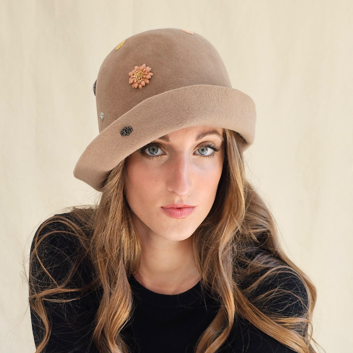 Camel felt cloche with flower and monogram embellishments,
worn on a model.