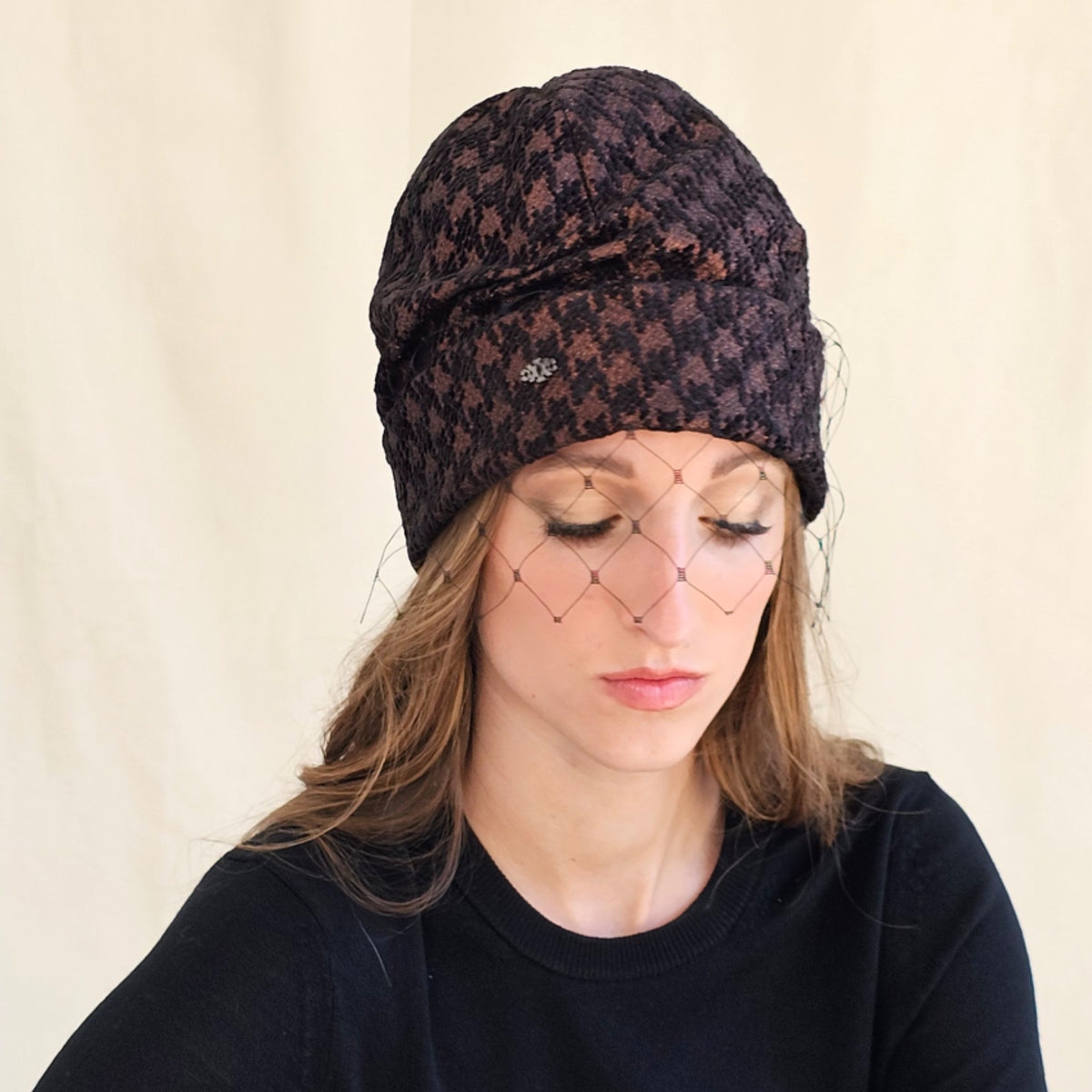 Close-up of brown metallic houndstooth beanie with face veil,
model looking down.