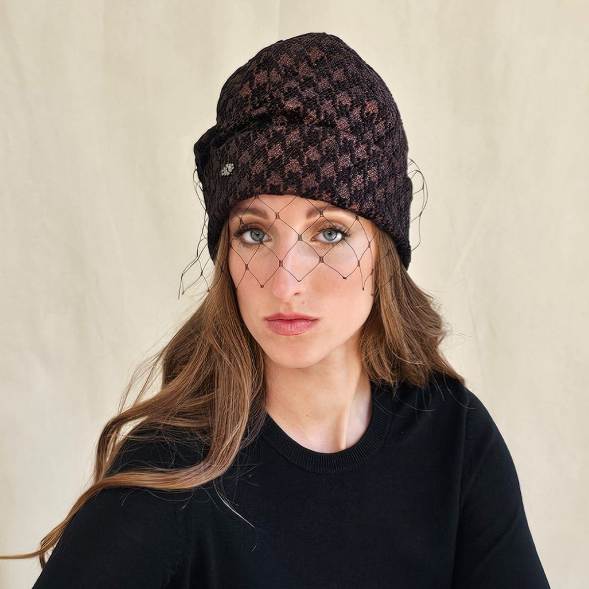 Brown metallic houndstooth beanie with black face veil, worn on a
model.