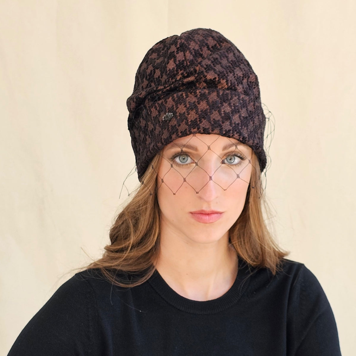 Front view of brown metallic houndstooth beanie with black net
veil.