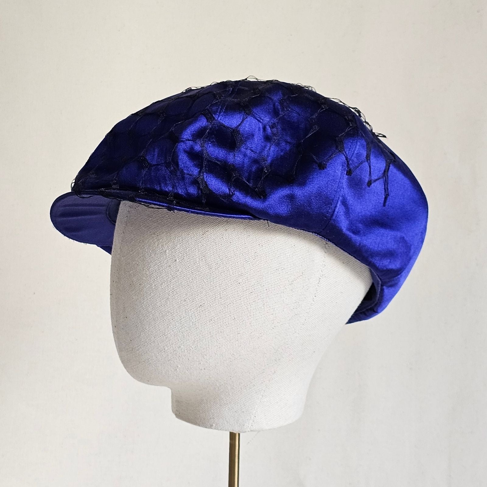 Cobalt silk baker boy hat with black veiling, left view.