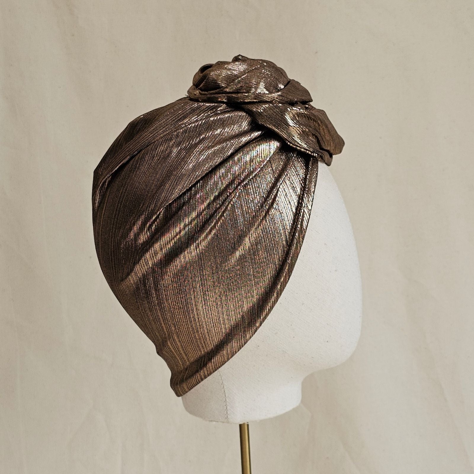 Copper lamé turban with sculpted rose knot, side view.