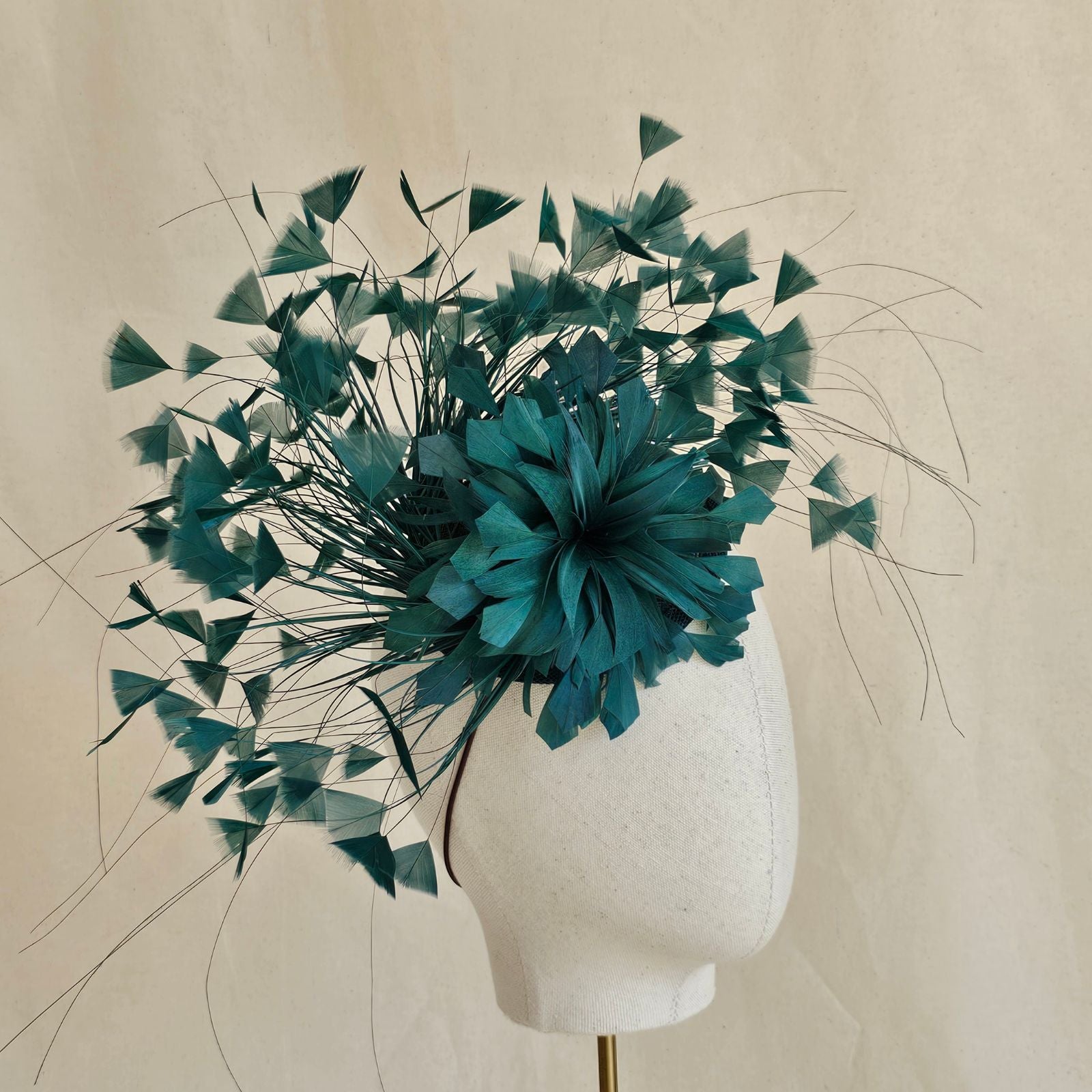 Emerald feather fascinator with feather flower, side view.