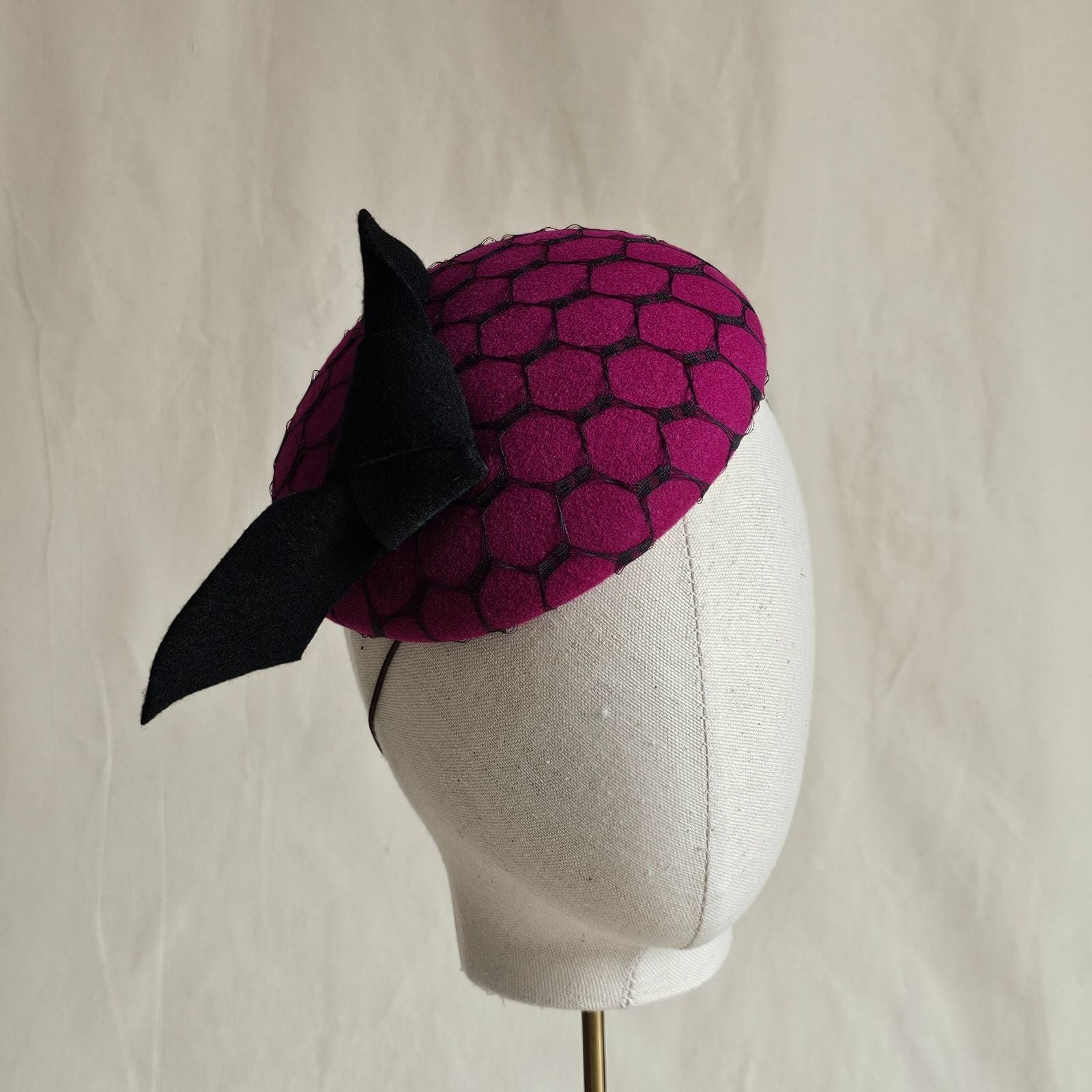 Fuchsia felt beret with black bow and veiling, angle view.
