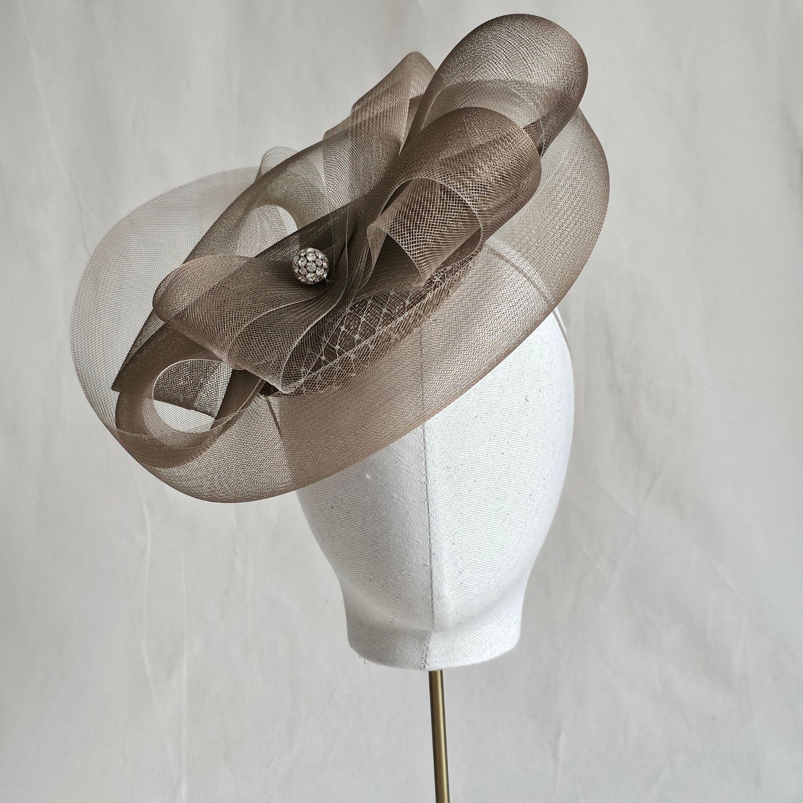 Gold fascinator with elegant crin swirls and crystal diamanté globe embellishment, front view.