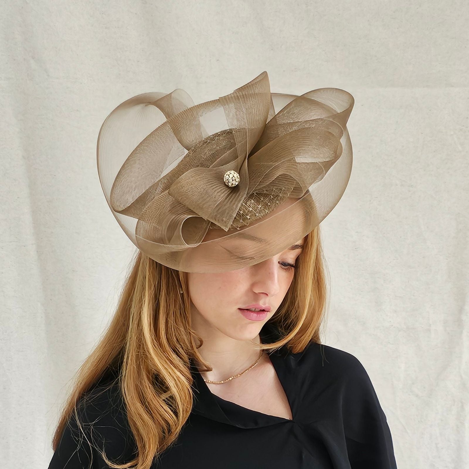 Gold fascinator with elegant crin swirls and crystal diamanté globe embellishment, angle view.