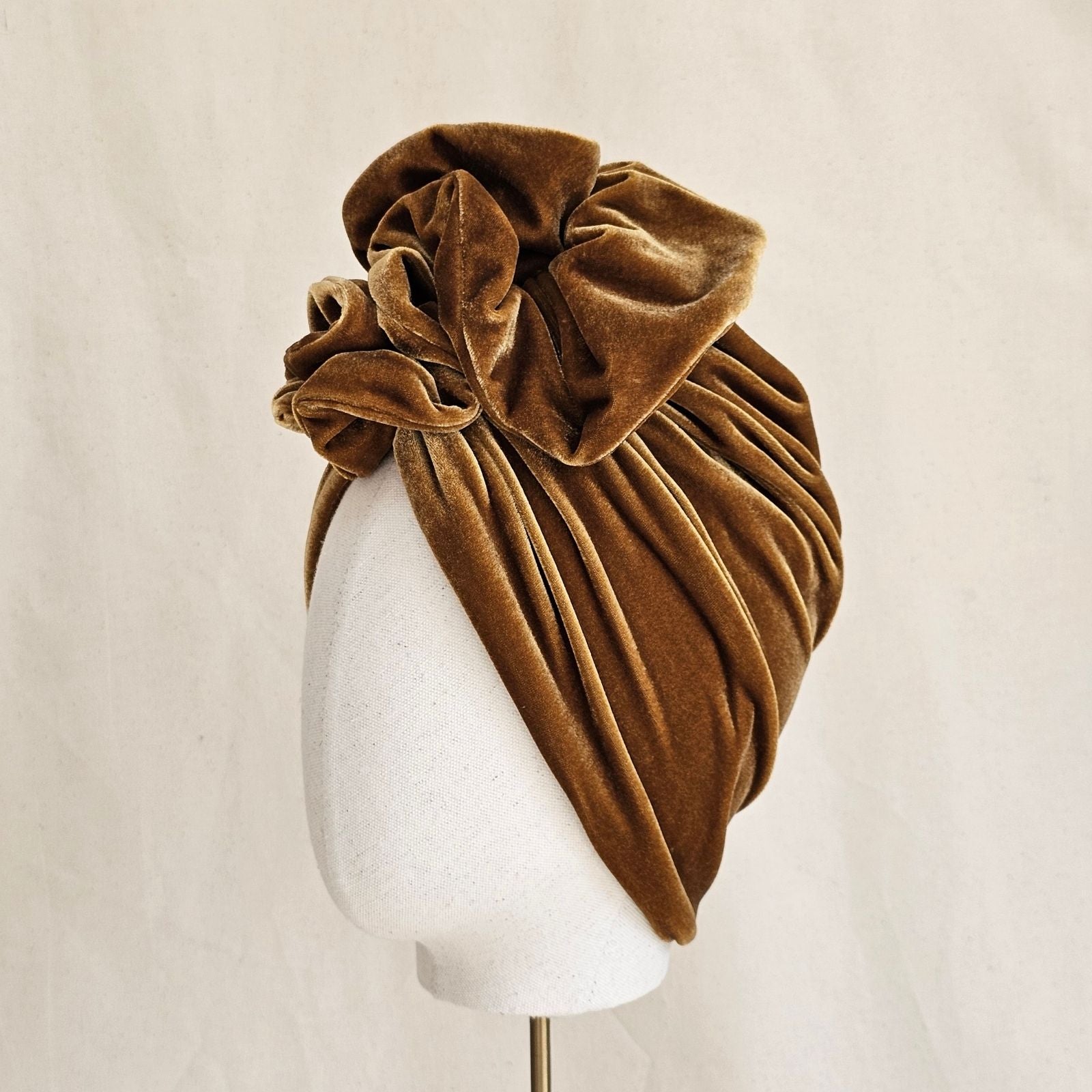 Gold velvet turban gathered into elegant ruffle, side view.