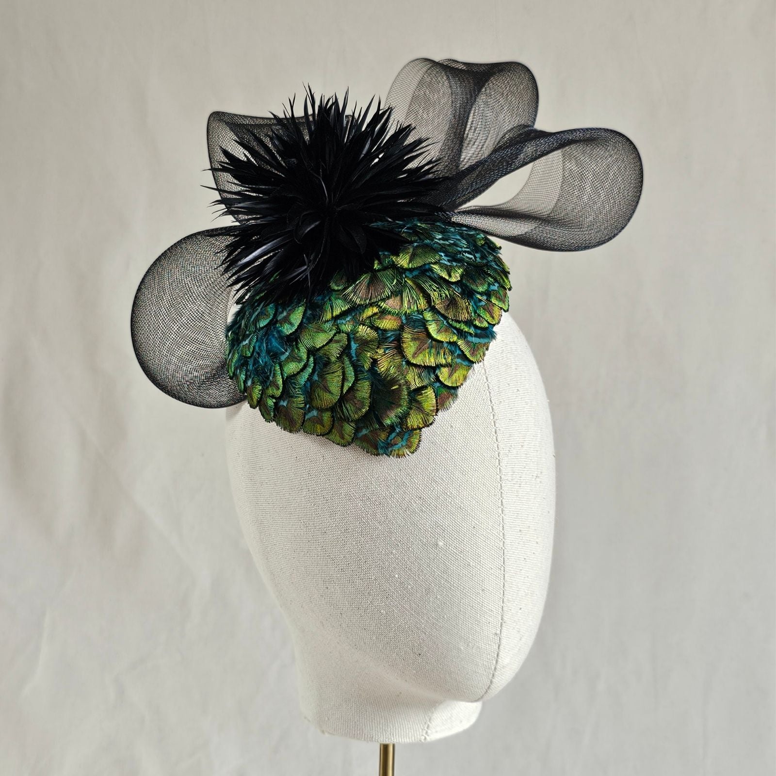 Green peacock feather hat with black feather flower and elegant crin swirl, front view.