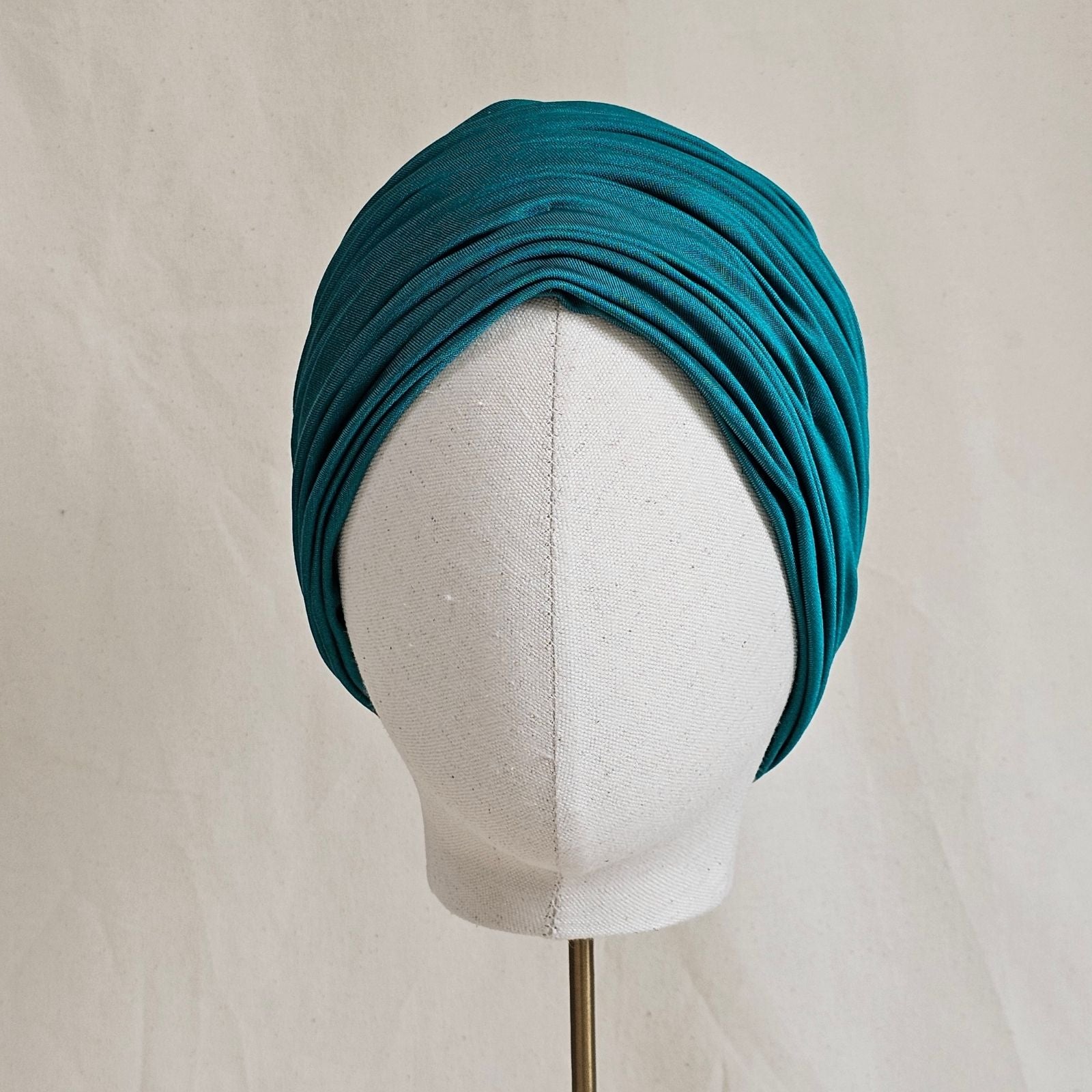 Green silk jersey turban with elegant gathers, front view.