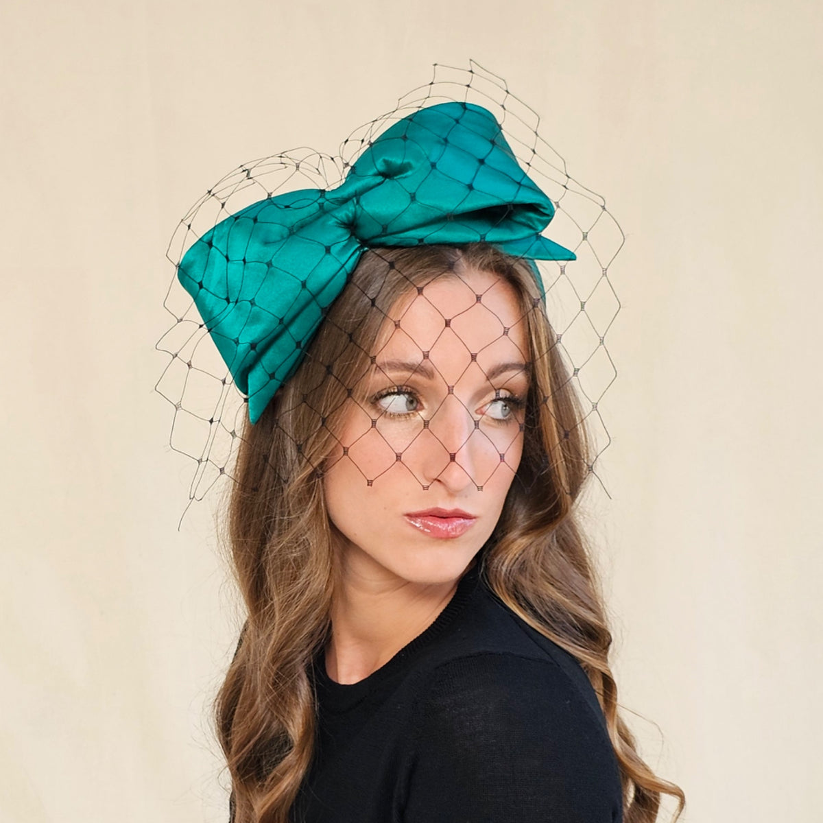 Emerald silk bow headband with black face veil, worn on a model.