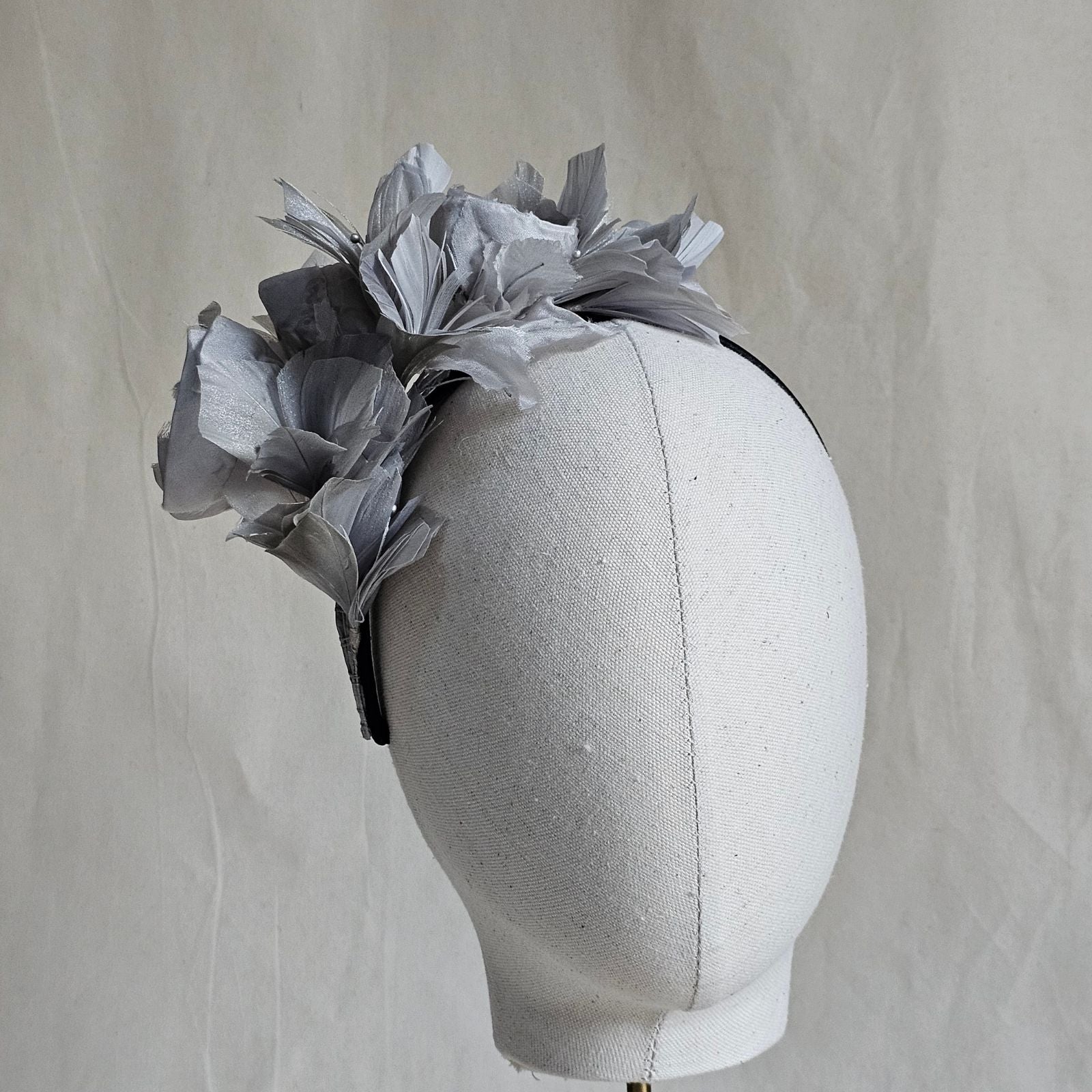 Headband with grey bud roses and feather flowers, front view.