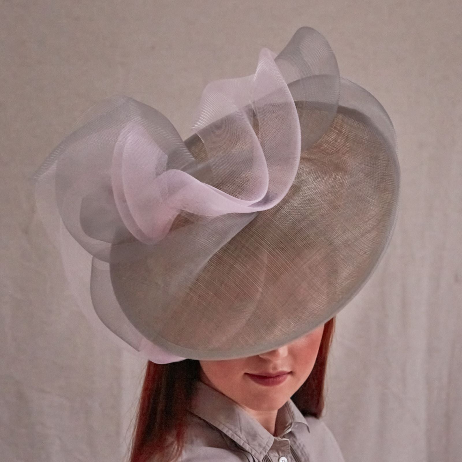 Grey and pink sinamay disc hat with elegant crin swirls, front view.
