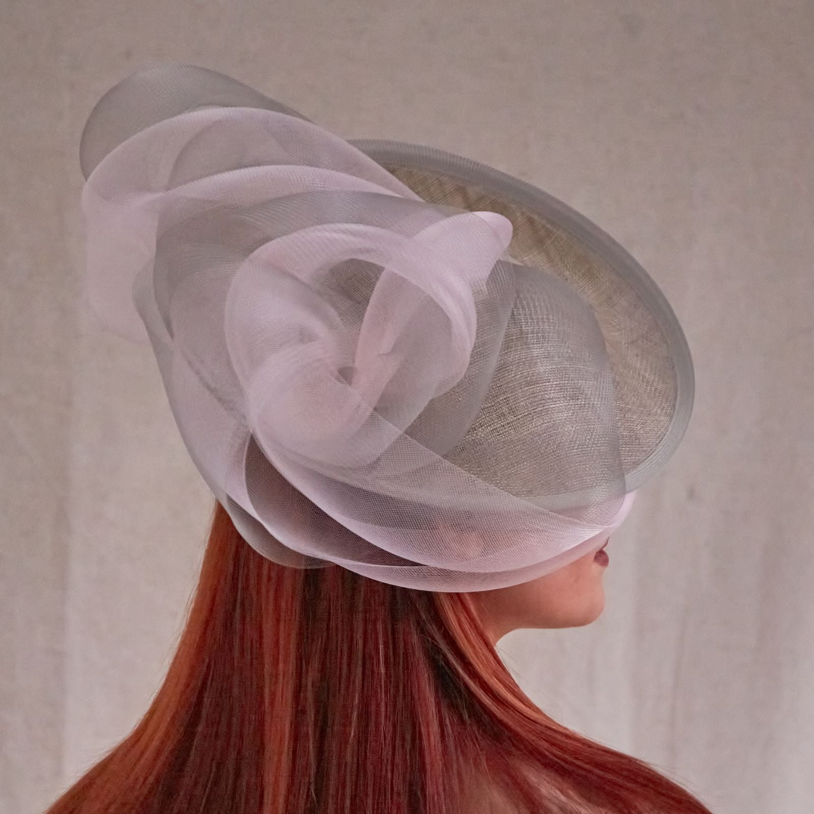 Grey and pink sinamay disc hat with elegant crin swirls, rear view.