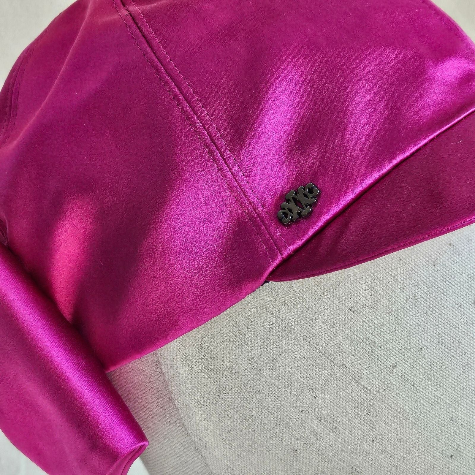 Detail of hot pink silk baseball cap with black Nerida Fraiman logo.