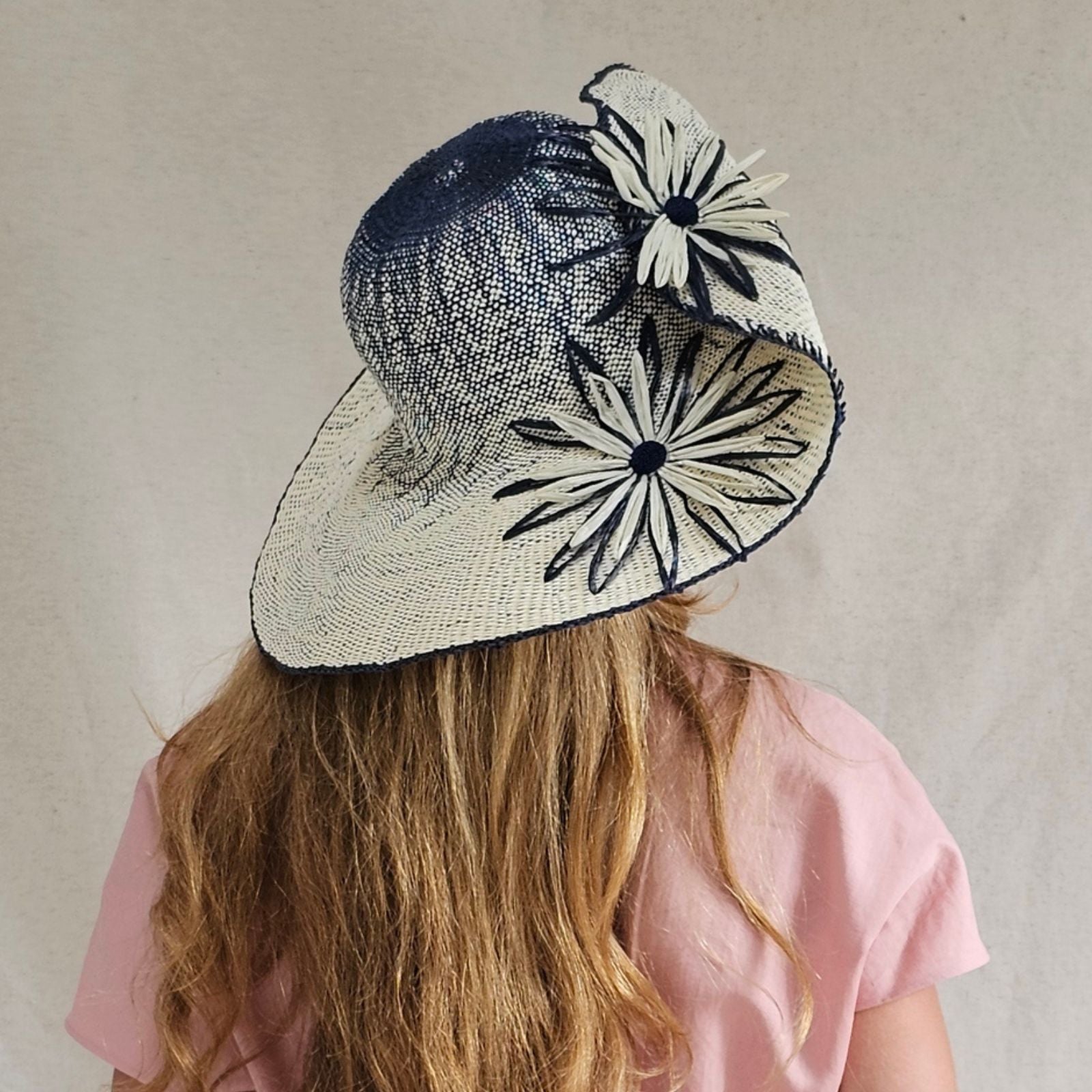 Ivory and blue straw sunhat with beautiful flower embellishments, rear view.